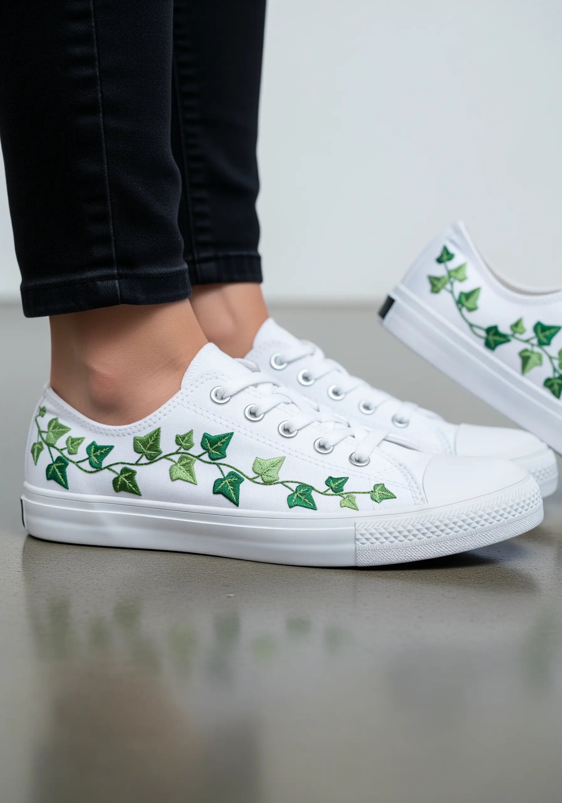 Green ivy vines embroidered along the sides of a pair of white canvas sneakers.