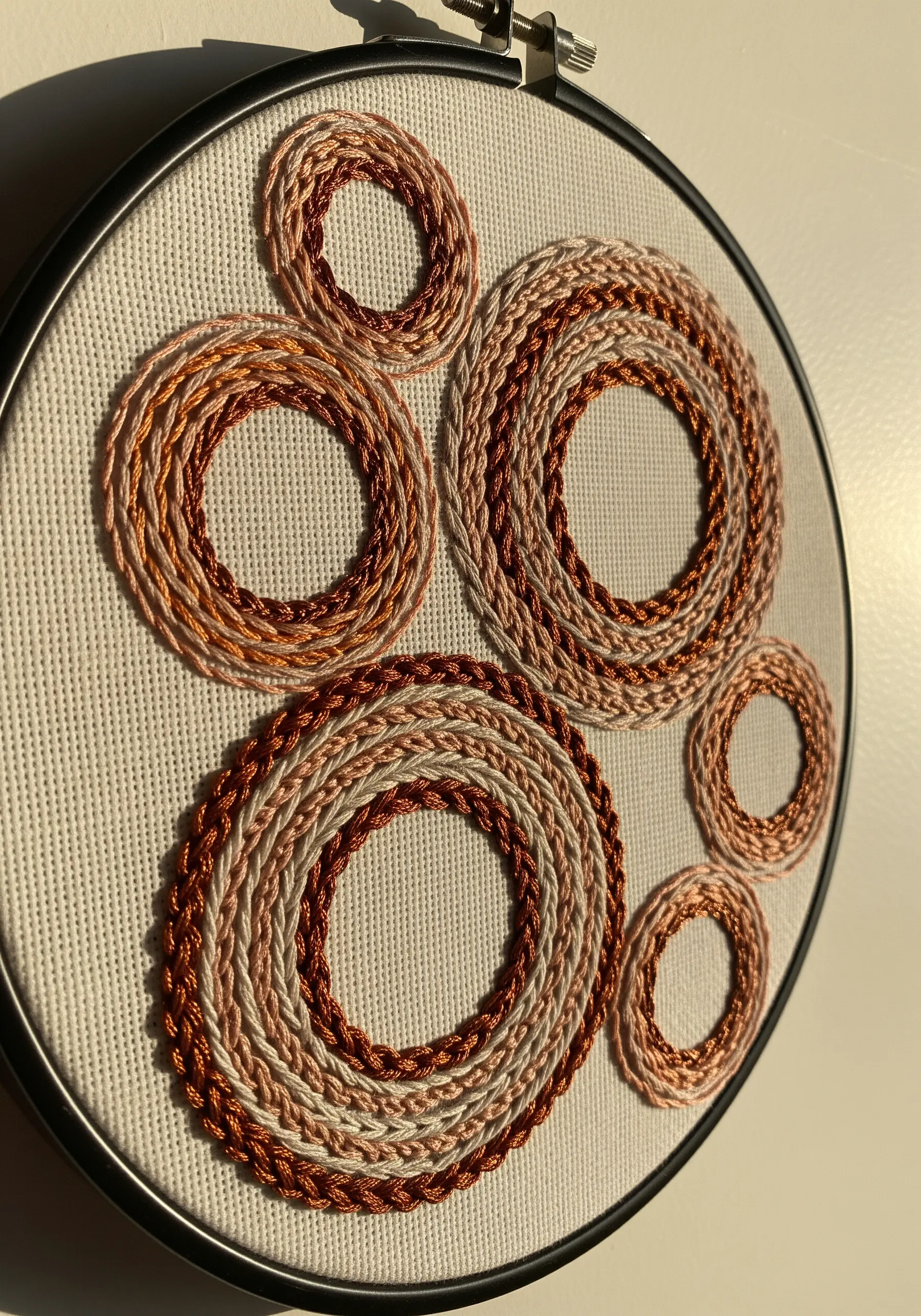 Abstract overlapping circles stitched with braided copper and rose gold metallic threads.