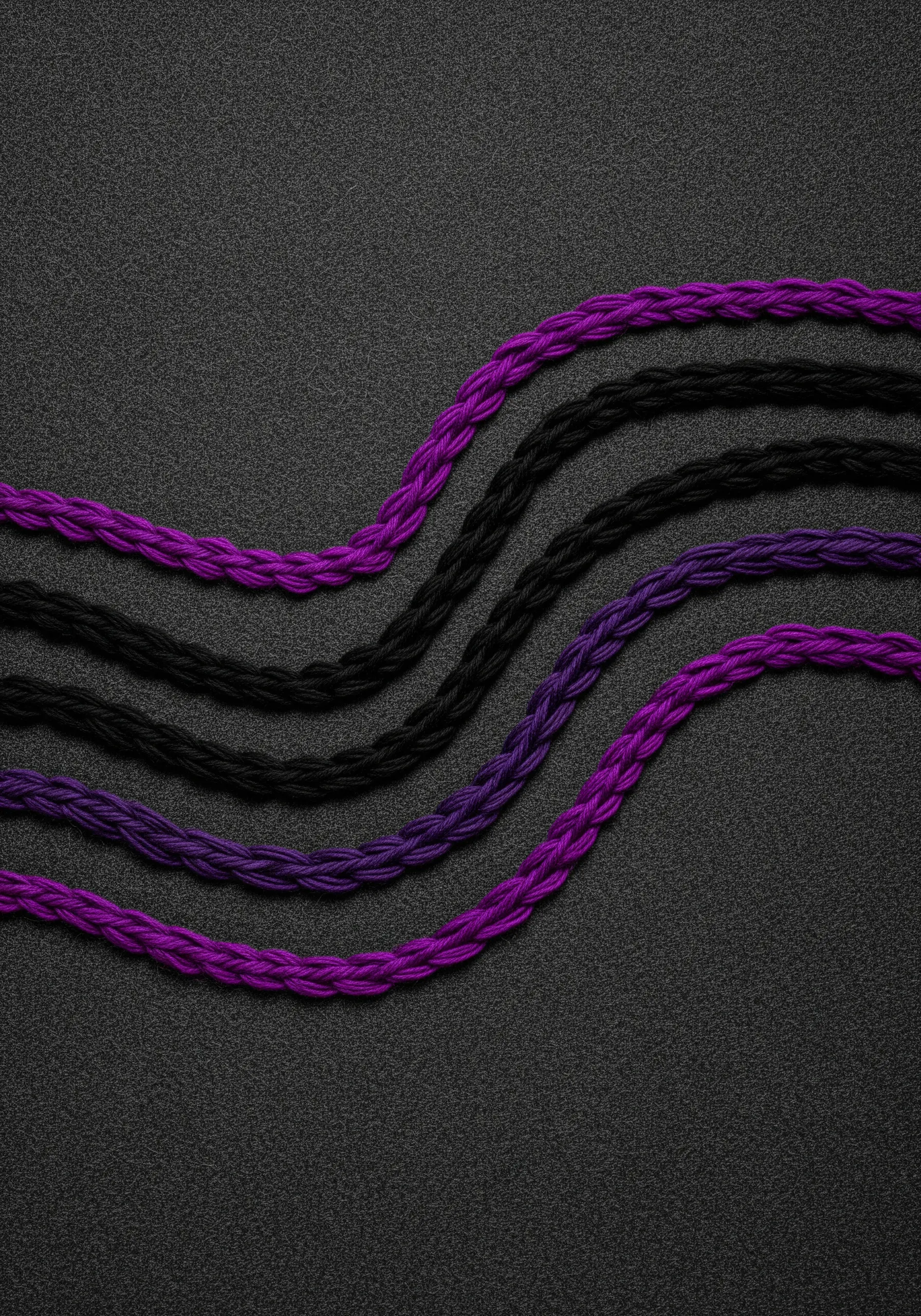 Thick, braided black and purple threads couched in a wavy pattern onto a dark background.