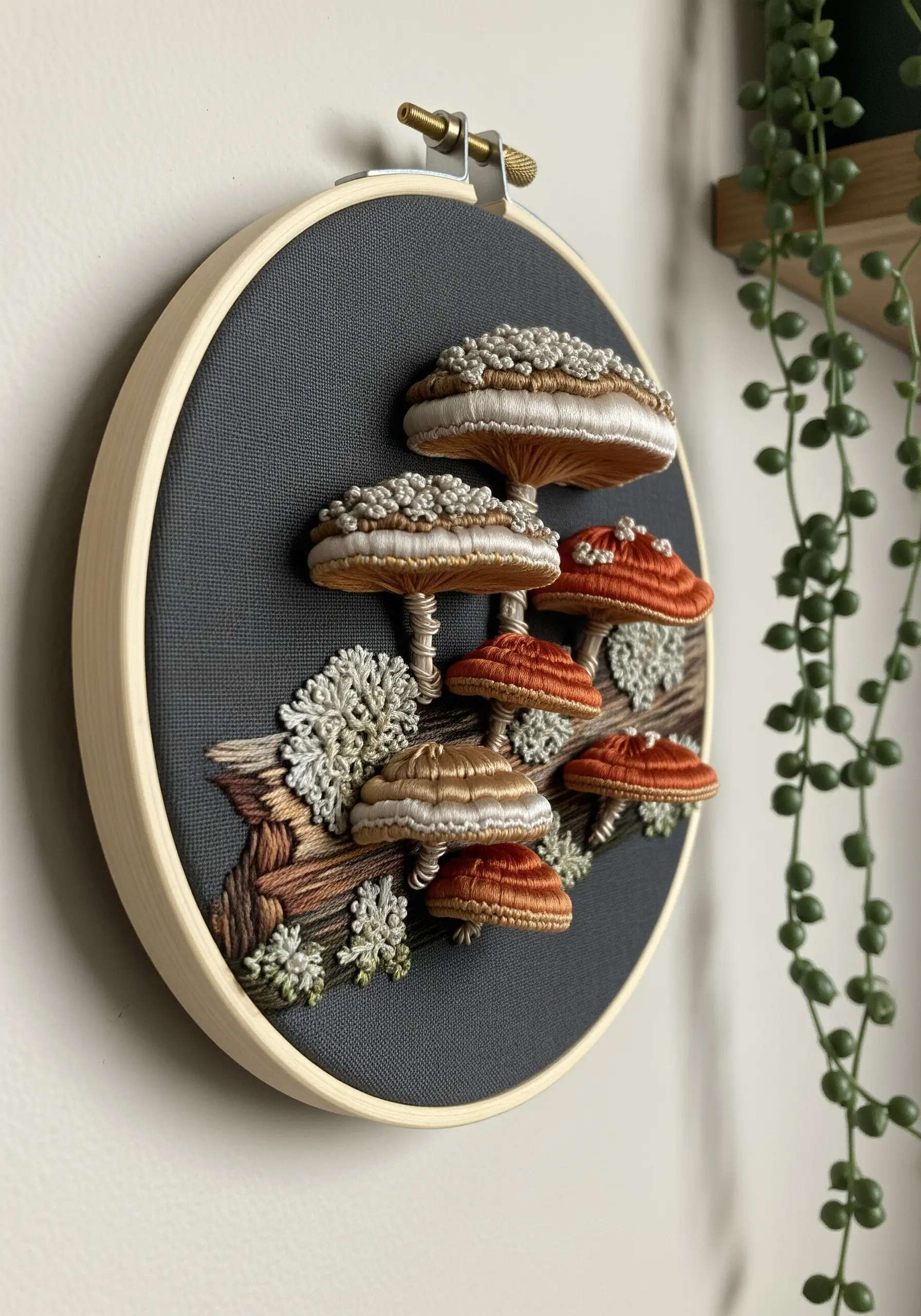 3D stumpwork mushrooms with textured caps and detailed gills embroidered on dark grey fabric.