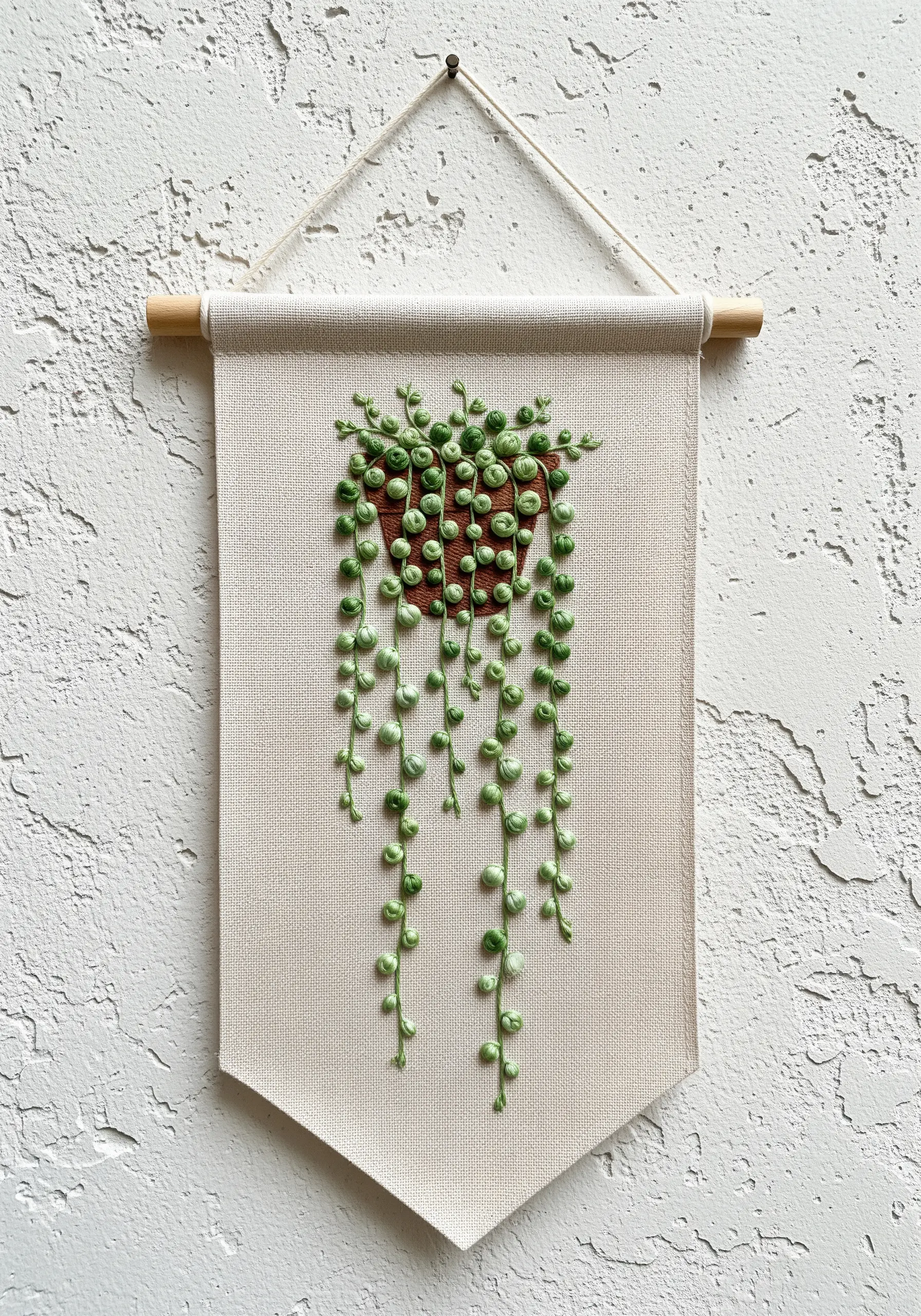 Embroidered String of Pearls plant with 3D French knots on a fabric banner.