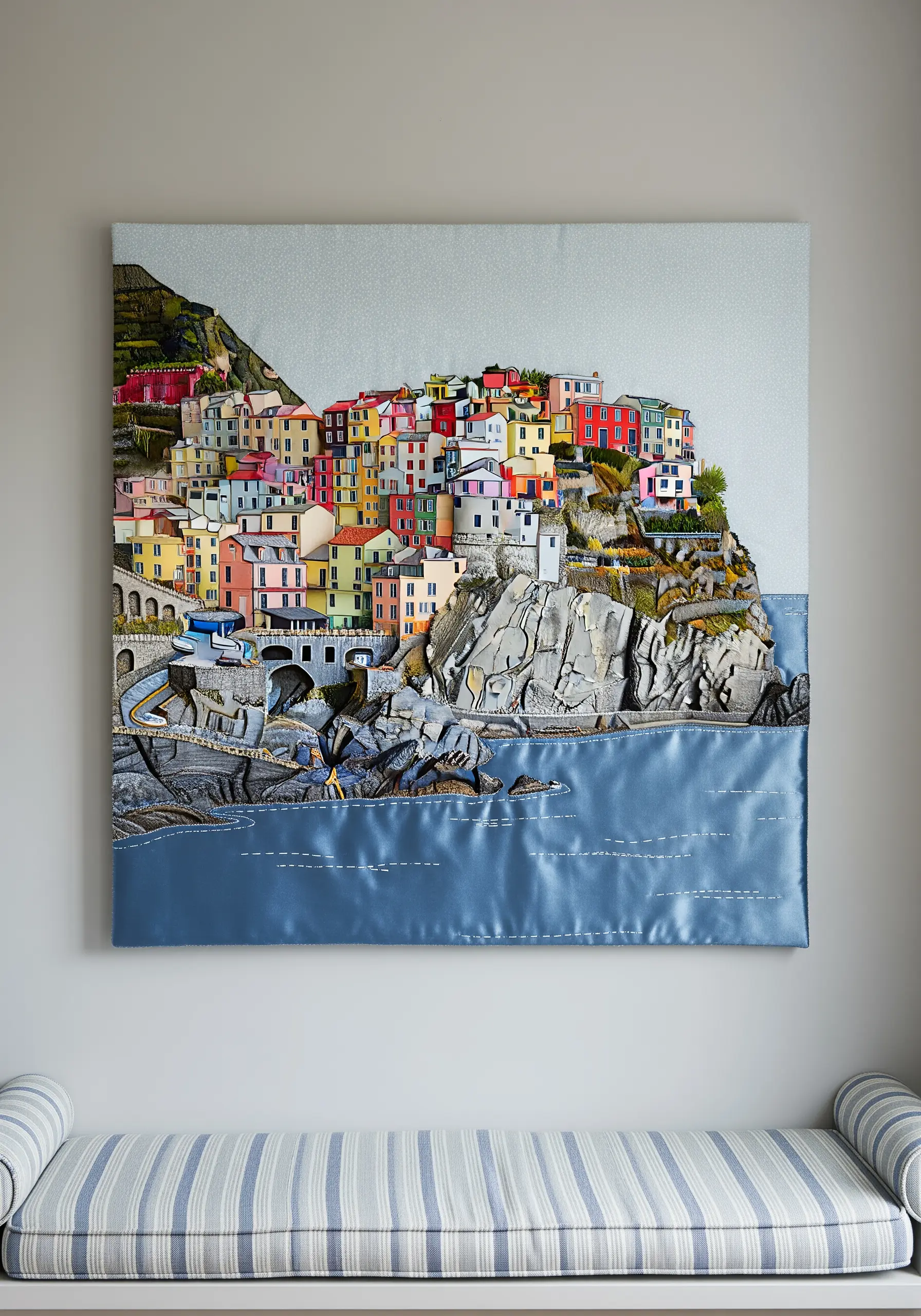 A complex fabric collage of a colorful coastal village perched on textured cliffs.