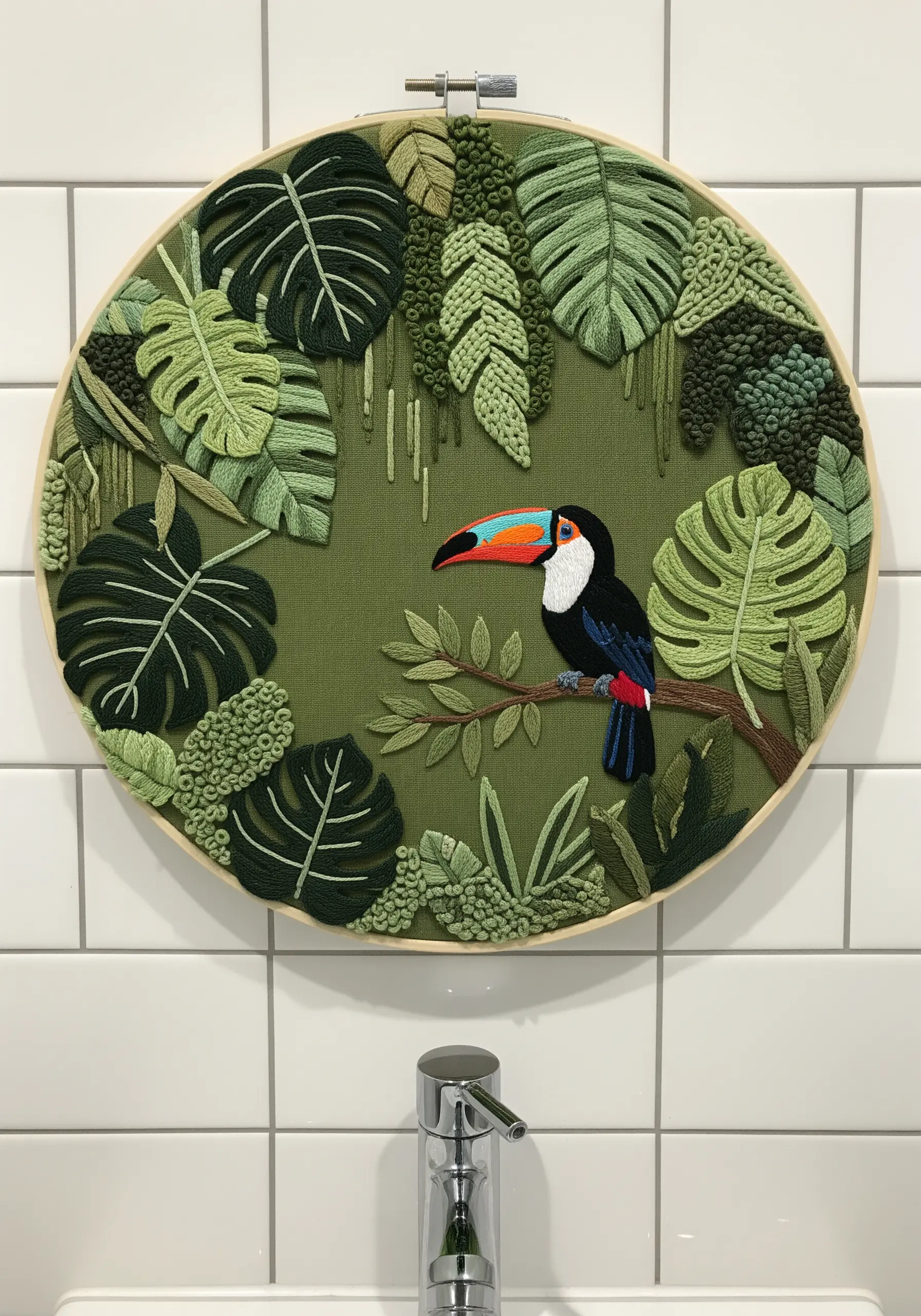A toucan surrounded by dimensional, layered embroidered leaves in various shades of green.