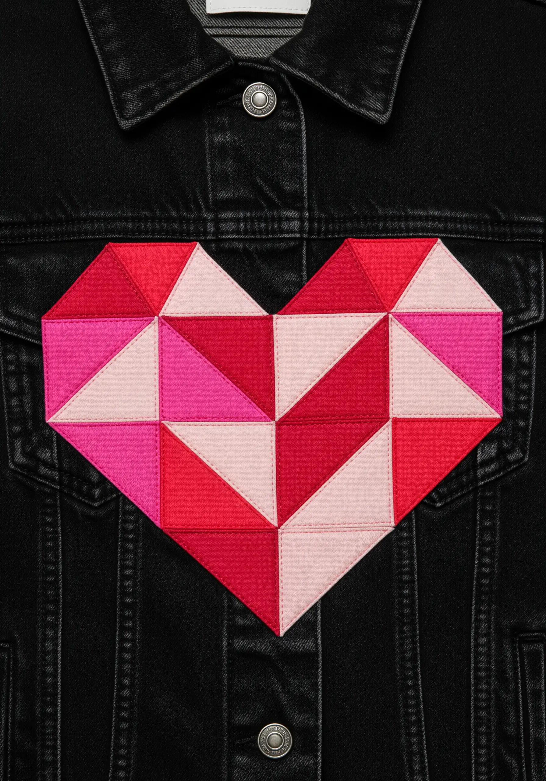 A heart motif made from a patchwork of pink and red fabric triangles on a black jacket.