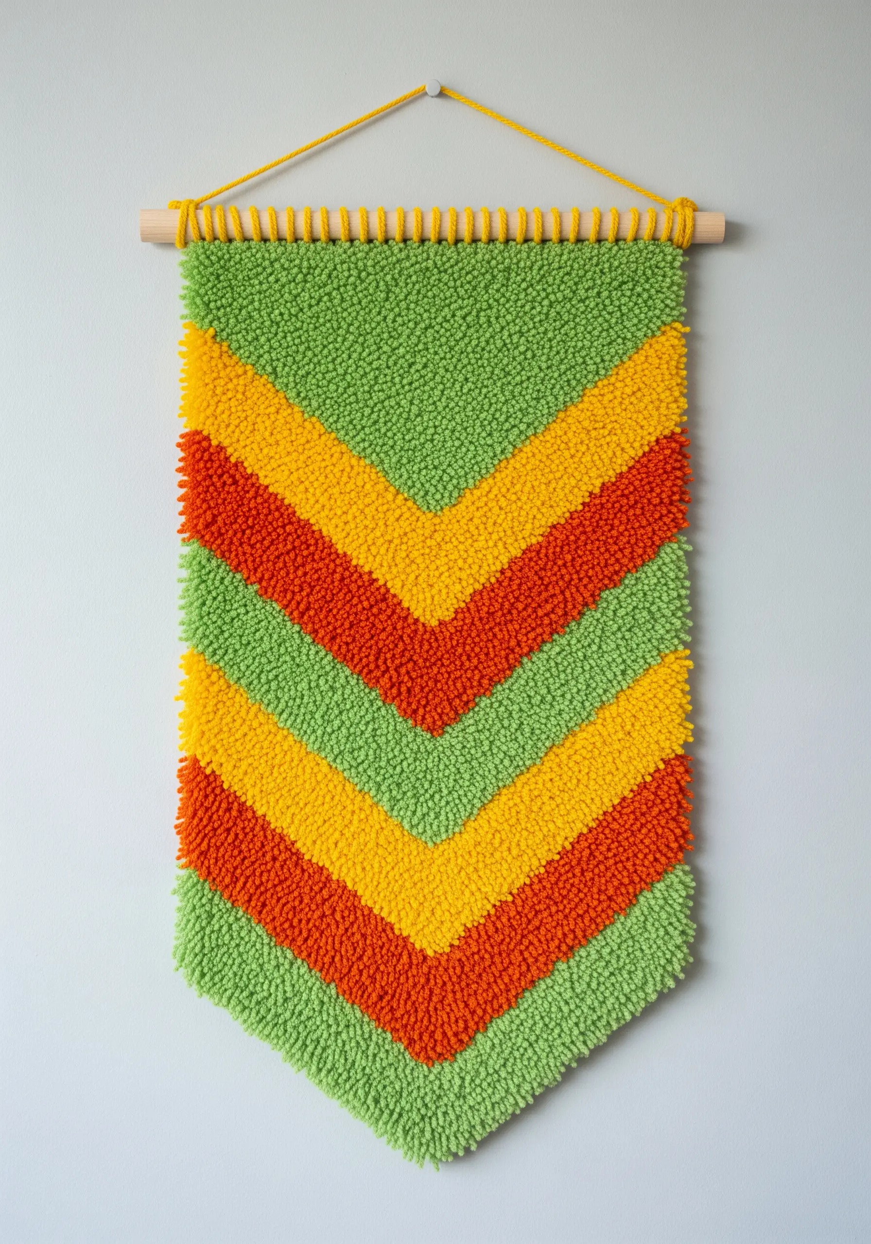 Latch hook wall hanging with a green, yellow, and orange chevron pattern.