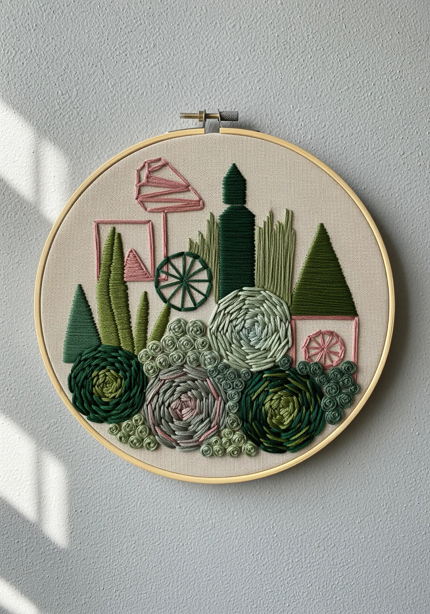 An abstract, textural embroidery hoop with woven wheels, satin stitches, and French knots in green and pink.