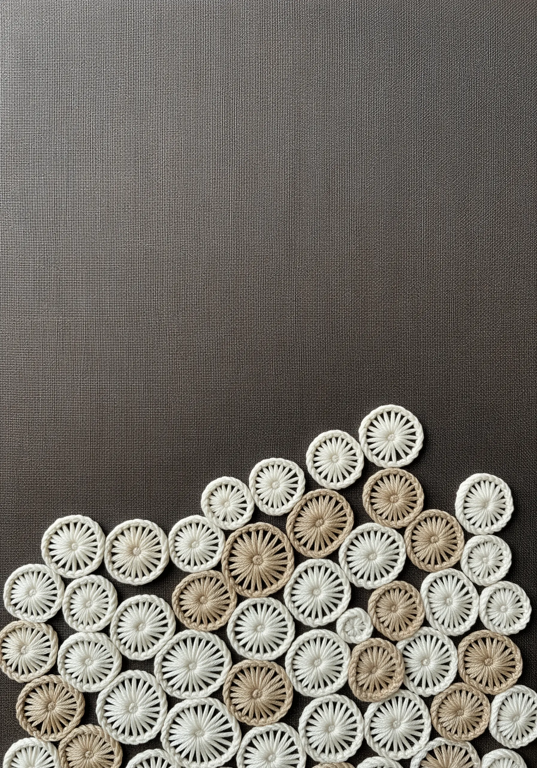 A cluster of woven wheel stitches in cream, white, and beige on a dark fabric.
