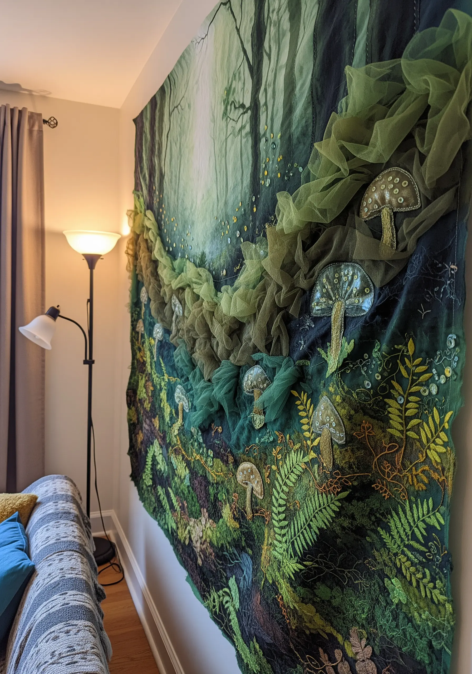 A large wall tapestry depicting a forest scene with 3D green tulle for moss and embroidered mushrooms.