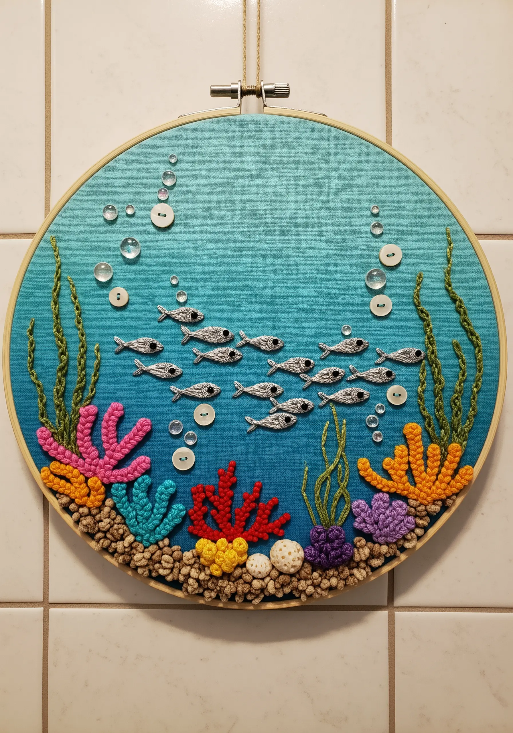 Embroidery hoop art of an underwater scene with button bubbles and French knot coral.