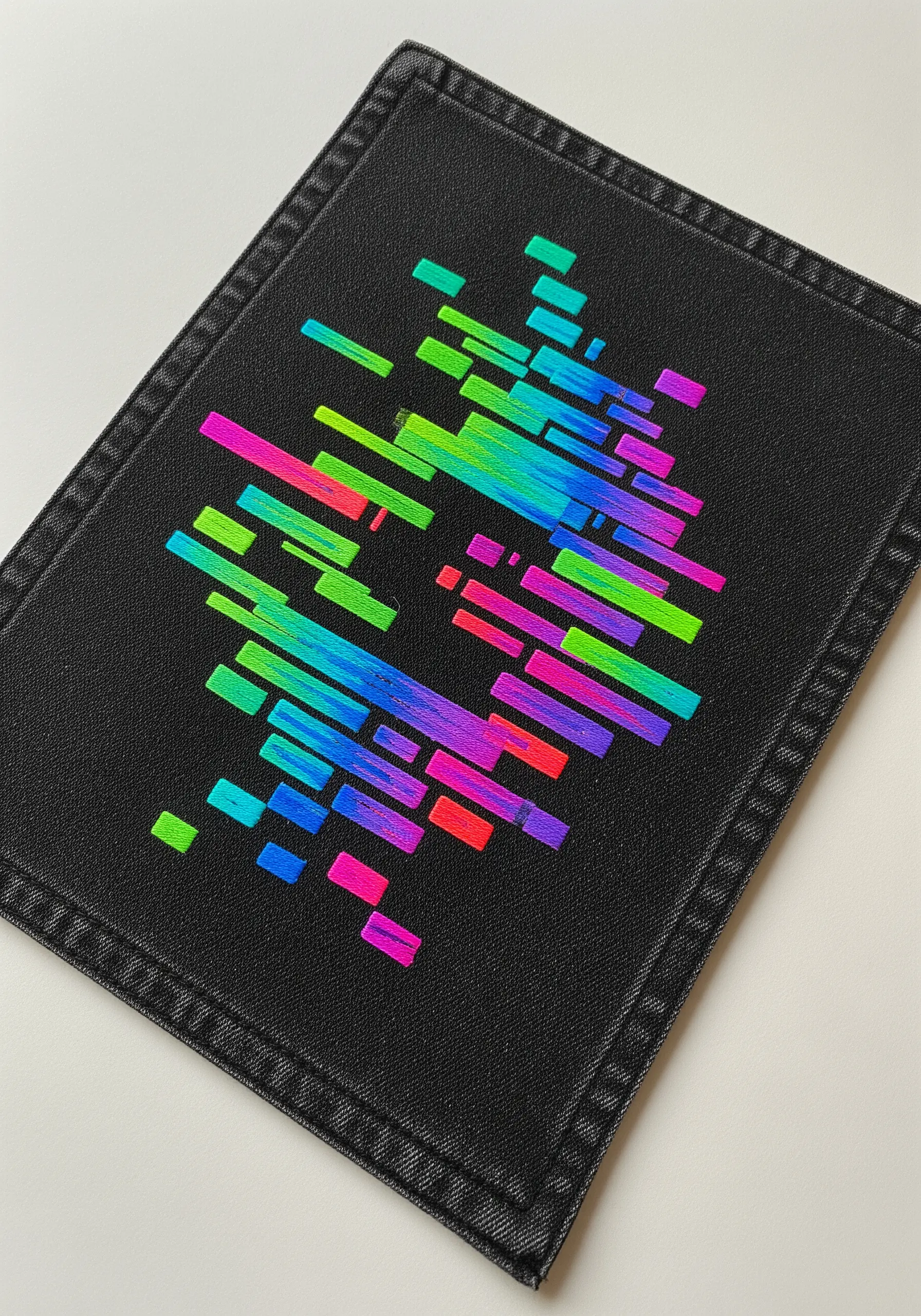 A patch with vibrant, geometric blocks of satin stitch in a neon gradient.