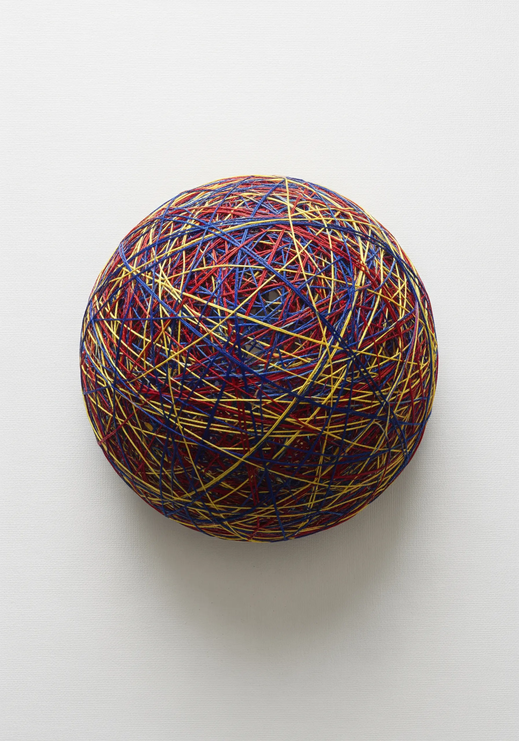 A dense, spherical shape created by layering thousands of straight stitches in primary colors.