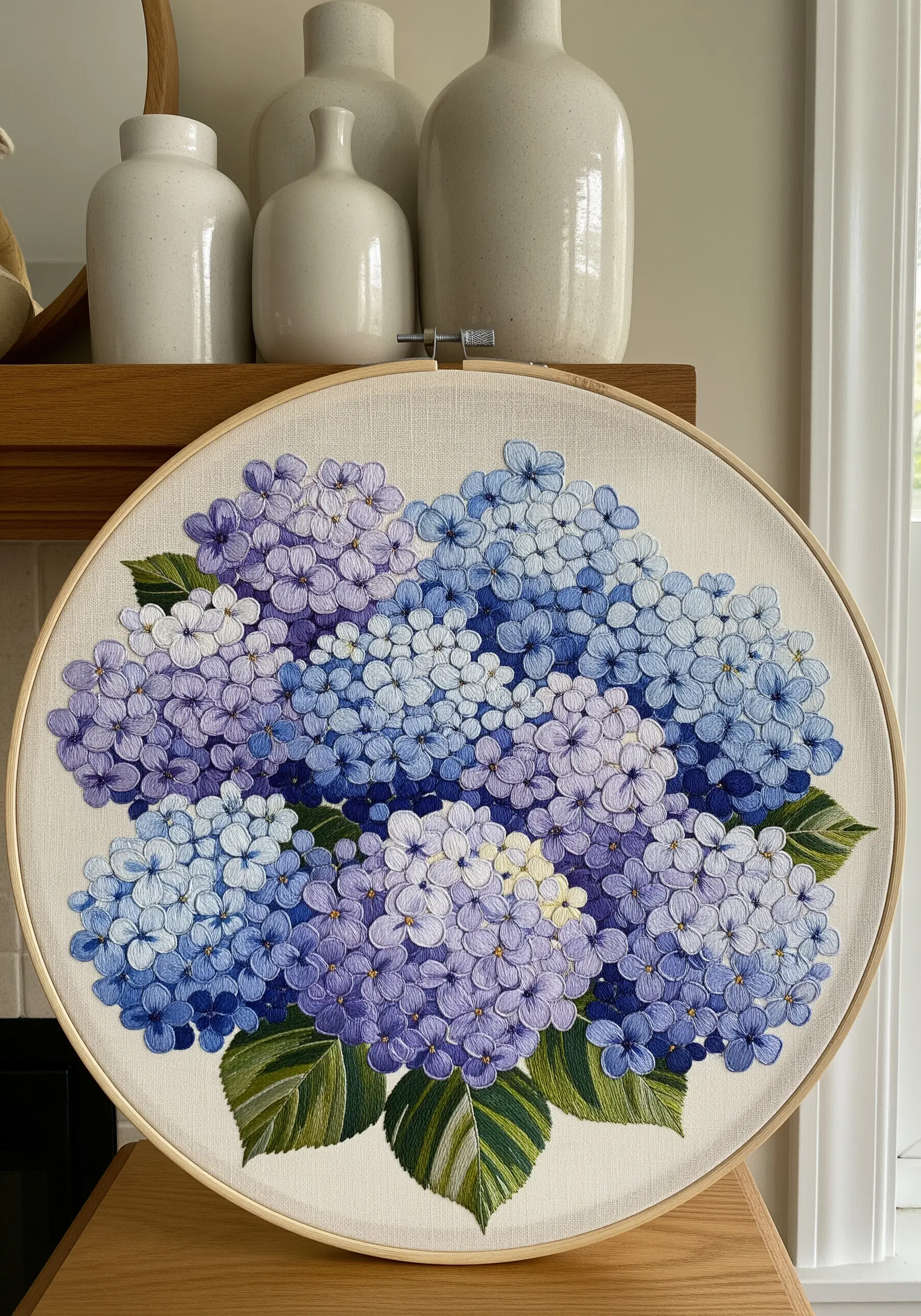 A large embroidery hoop filled with dense clusters of blue and purple hydrangea flowers.