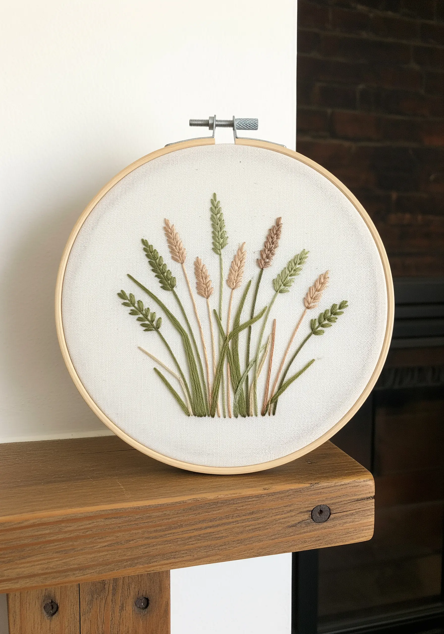 A cluster of embroidered wild grasses in various green and beige tones on white fabric.