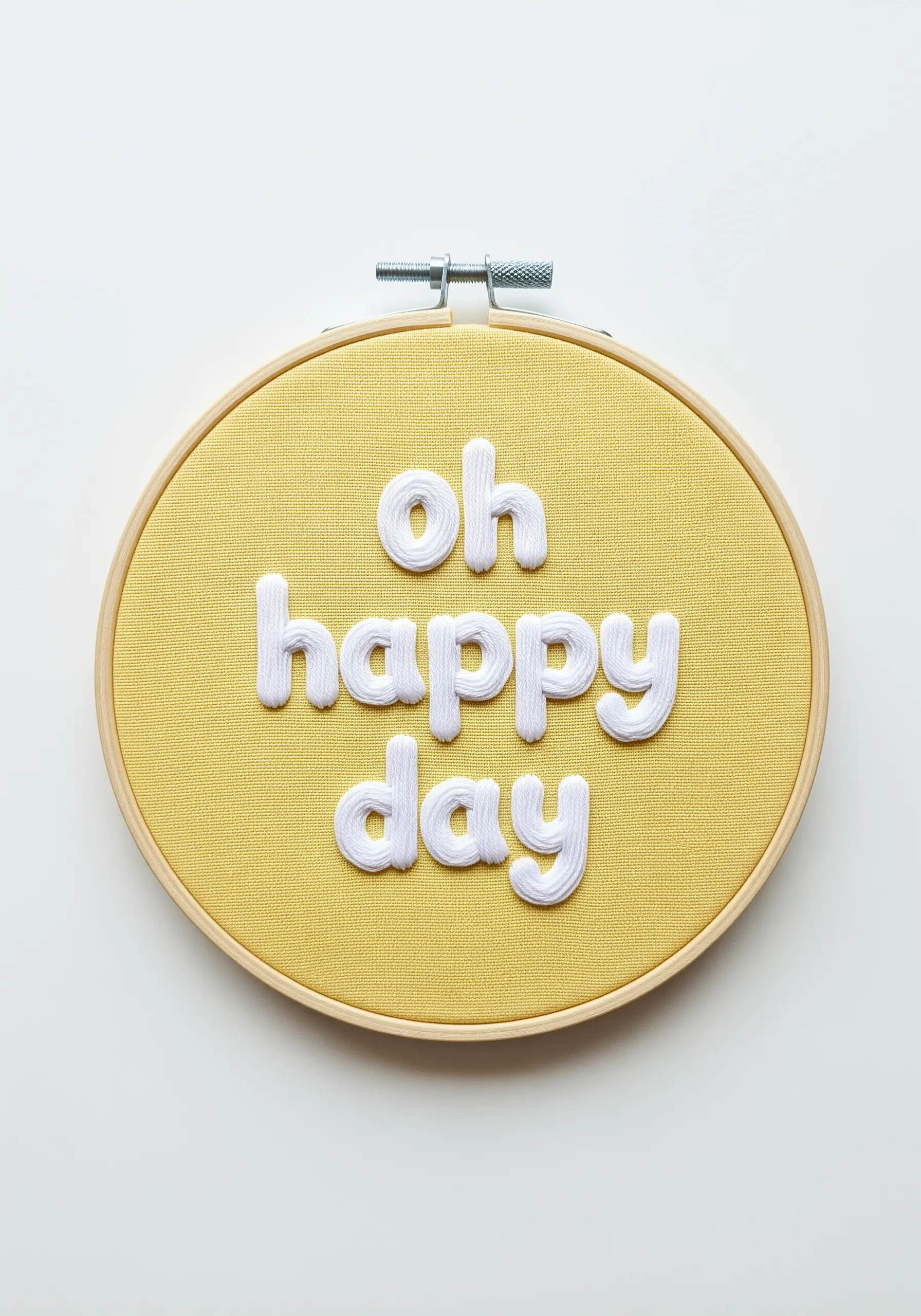 Puffy white letters spelling 'oh happy day' on yellow fabric using a padded satin stitch.