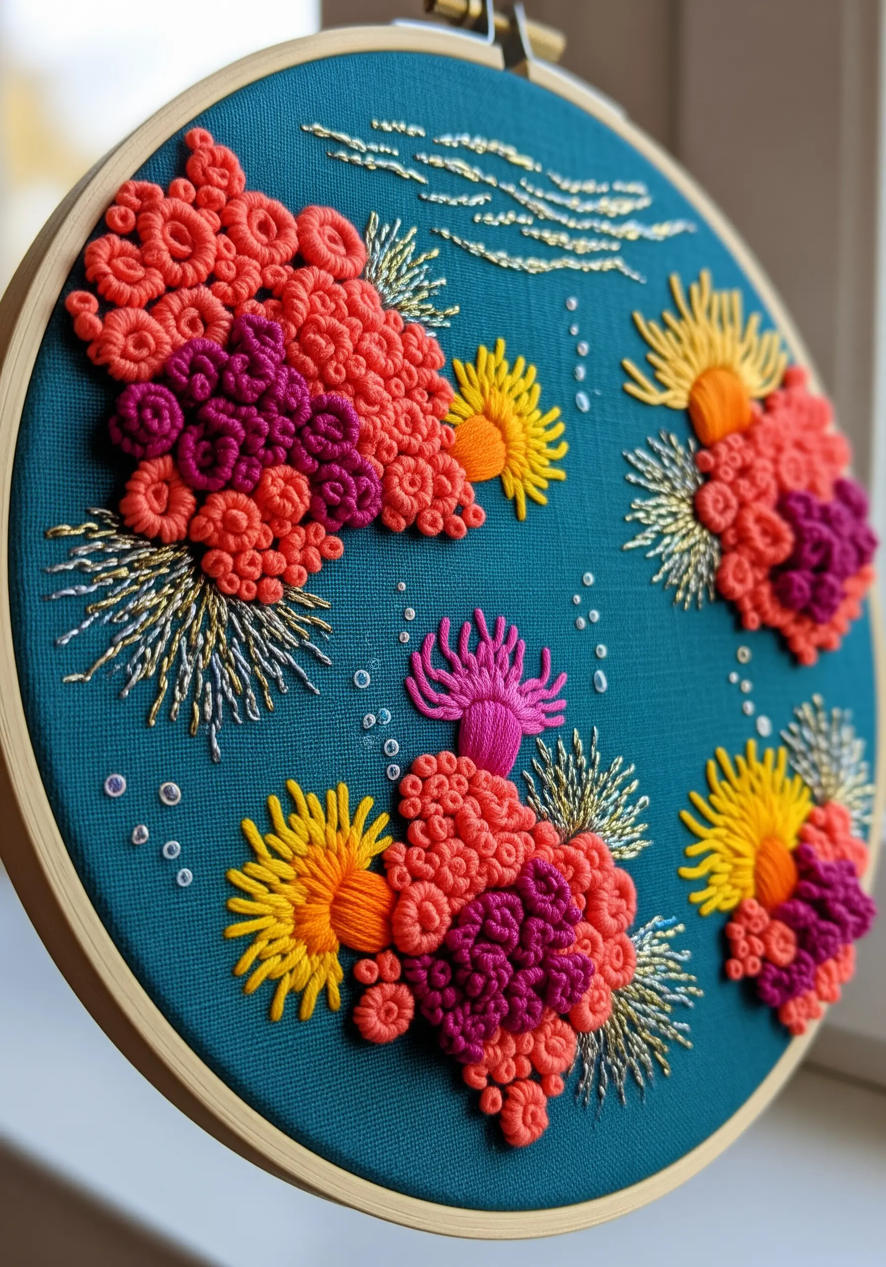 Densely packed French knots and metallic thread create a vibrant coral reef embroidery hoop.
