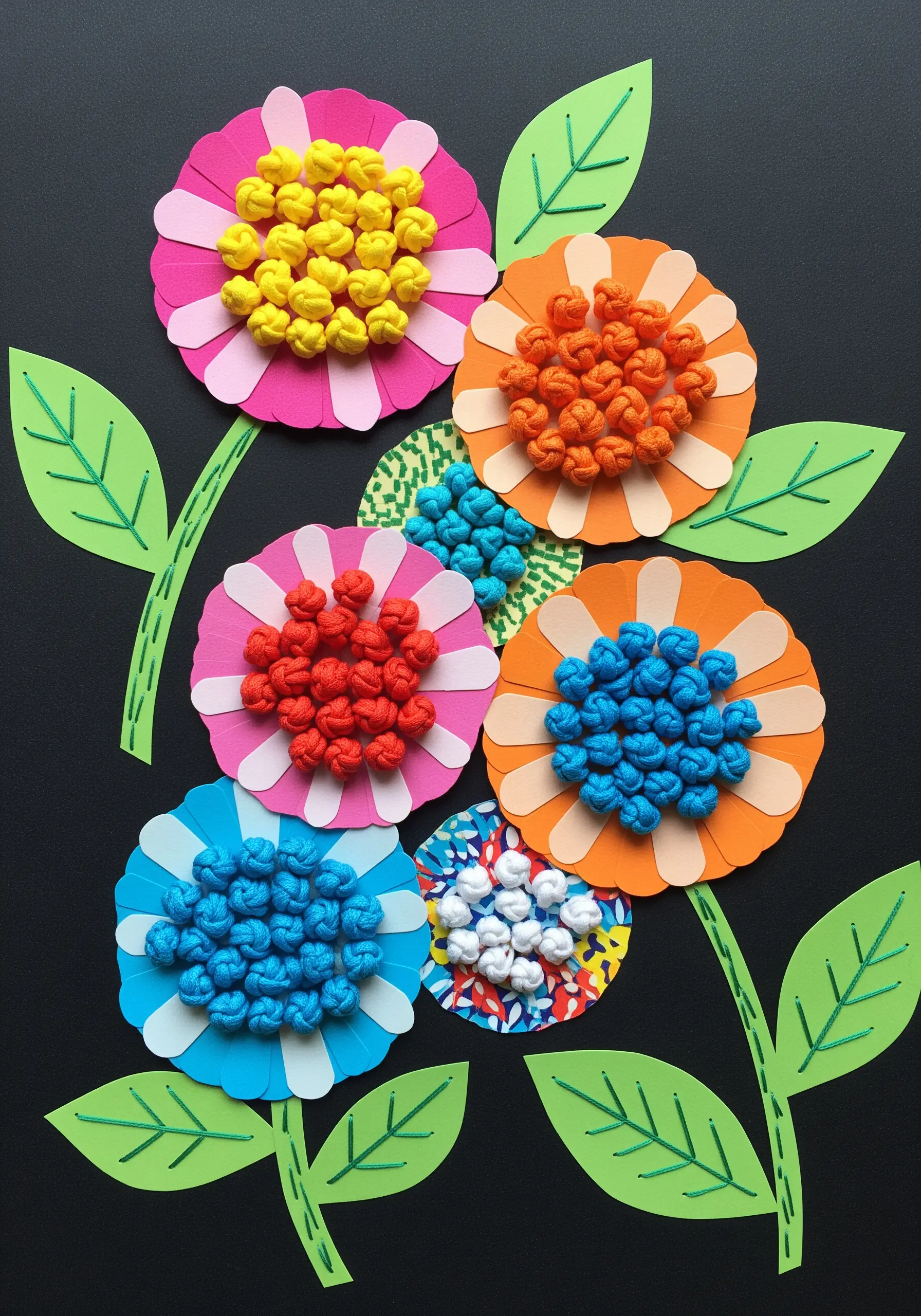 Colorful paper flowers with their centers filled with dense clusters of embroidered knots.