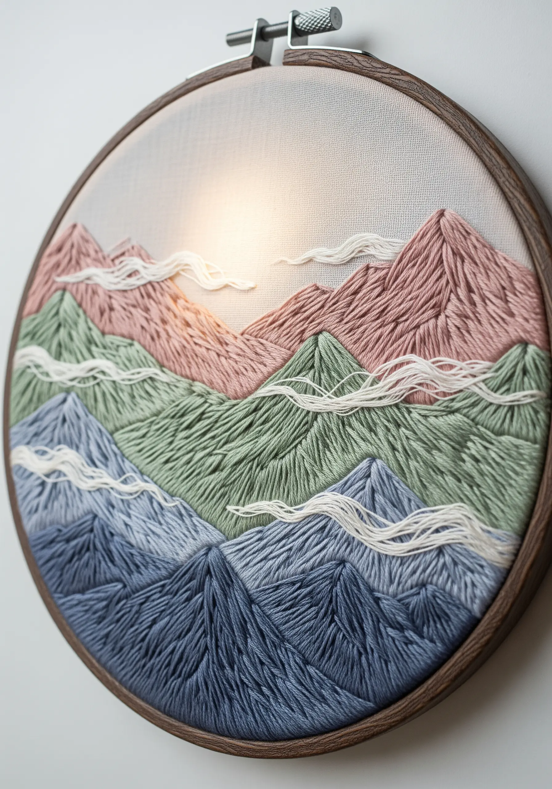 Layered mountain landscape embroidery with directional stitching in soft pastel colors.