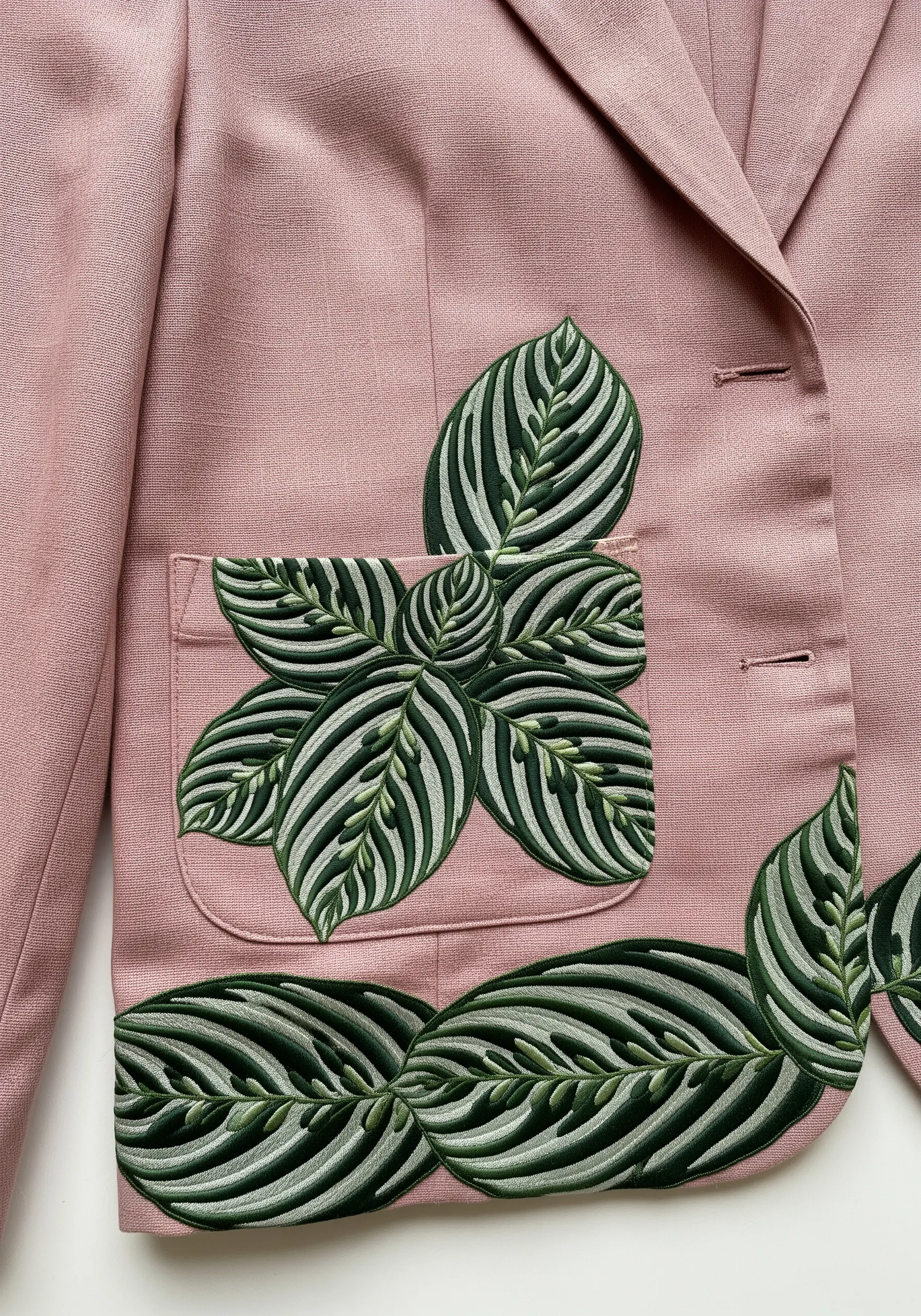 Striped calathea leaves embroidered on the pocket and hem of a pink blazer.