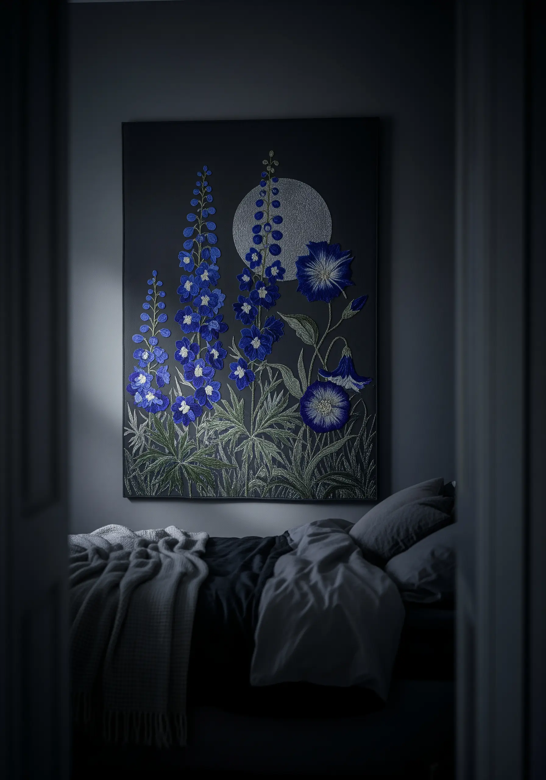 A large canvas with embroidered blue delphiniums and a silver moon, hanging in a dark bedroom.