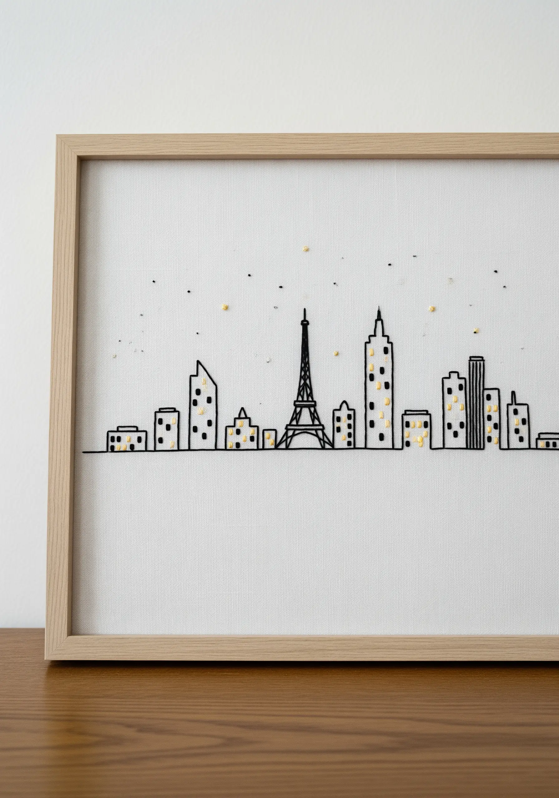 Minimalist black line embroidery of a city skyline with tiny yellow French knot windows