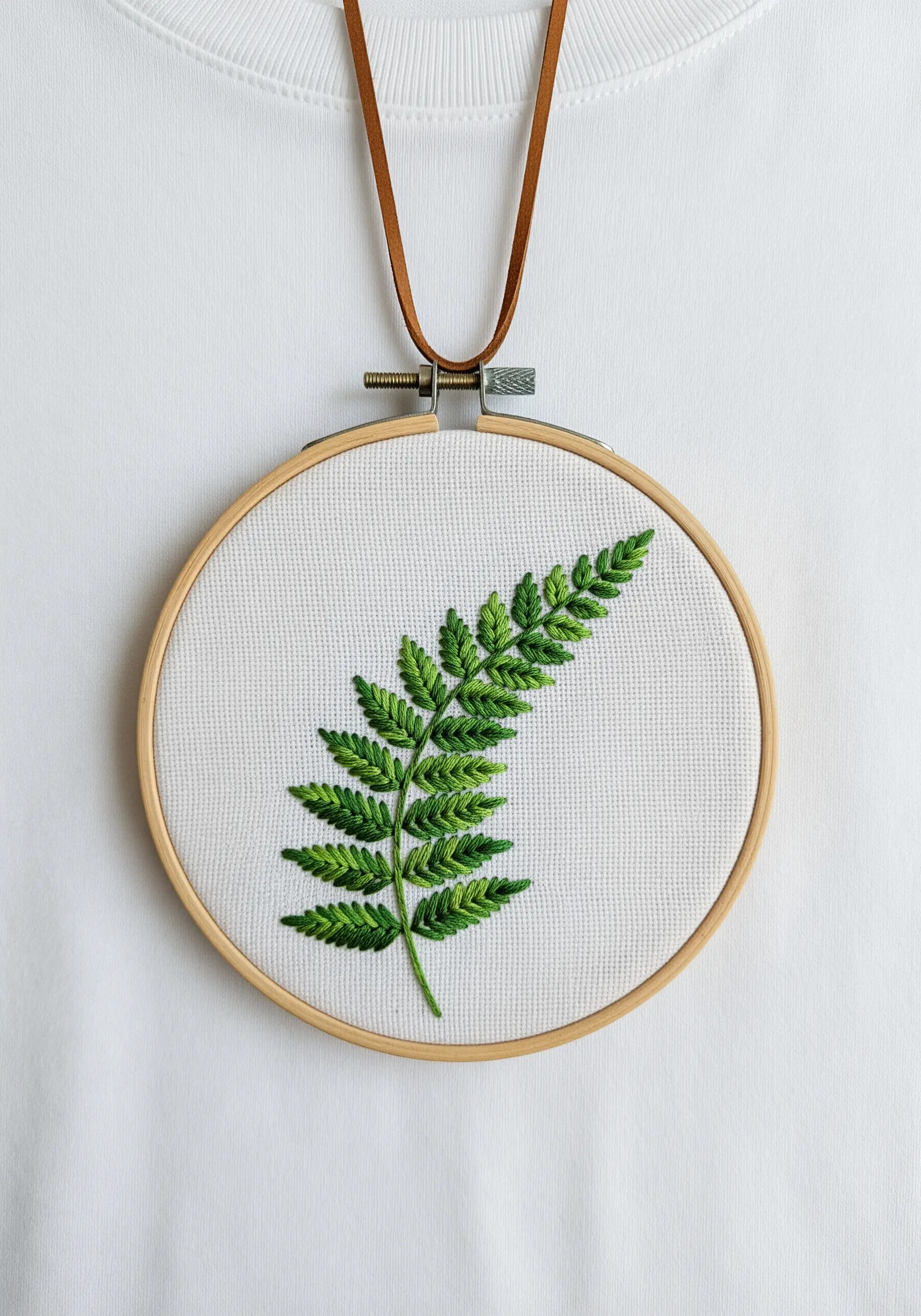 A single fern frond embroidered with fishbone stitch showing a natural gradient of green.