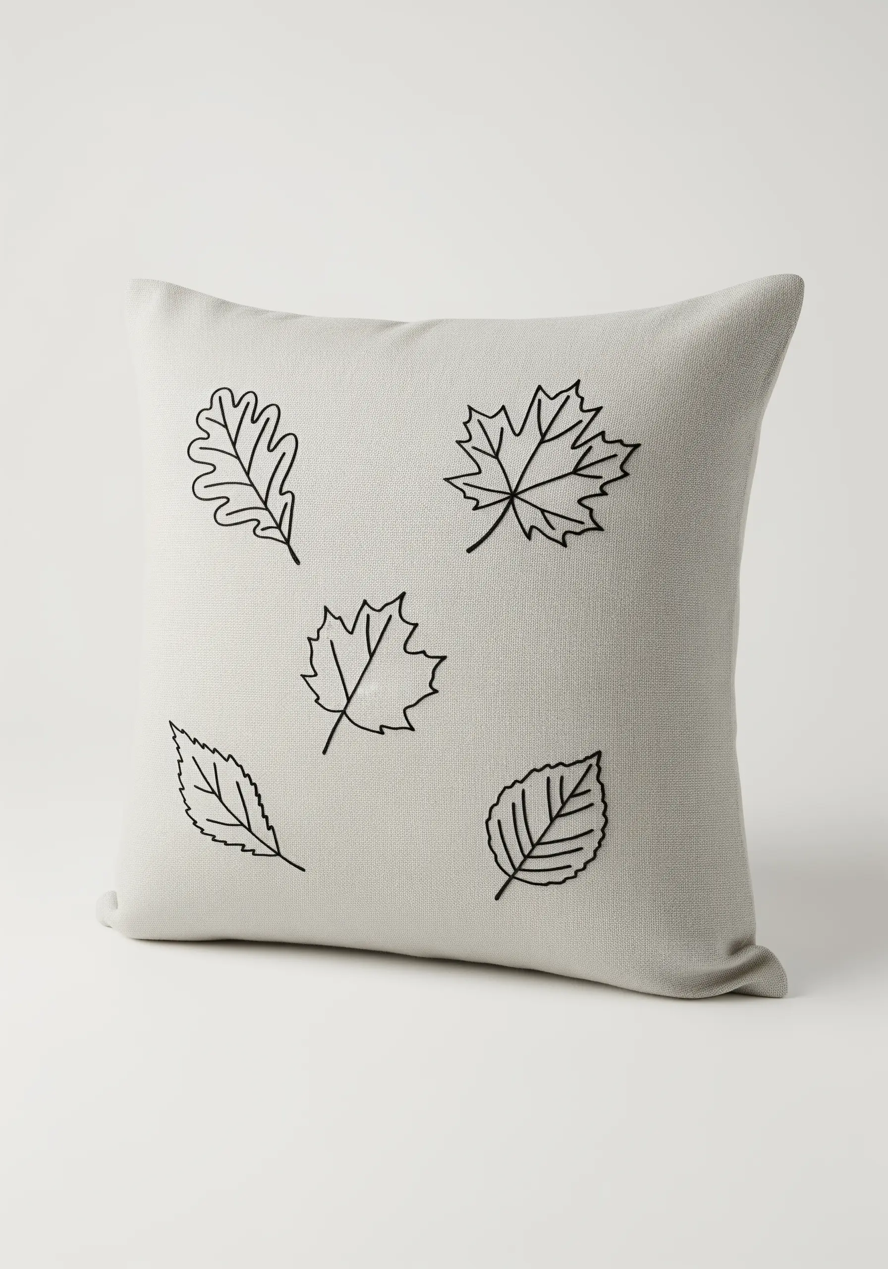 Scattered autumn leaf outlines embroidered in black on a light grey, textured cushion.