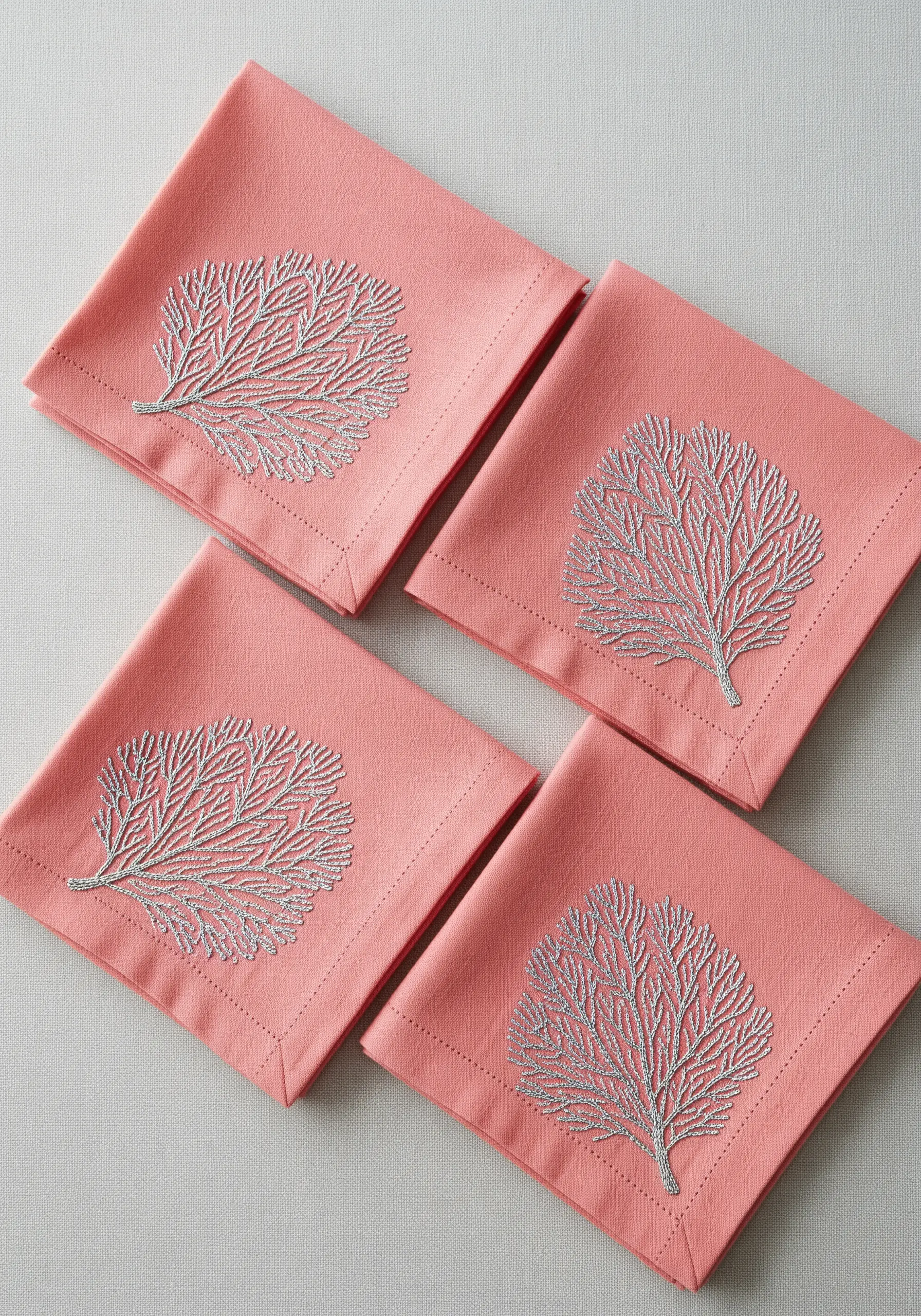 Coral-pink napkins with a delicate sea coral motif embroidered in sparkling silver metallic thread.