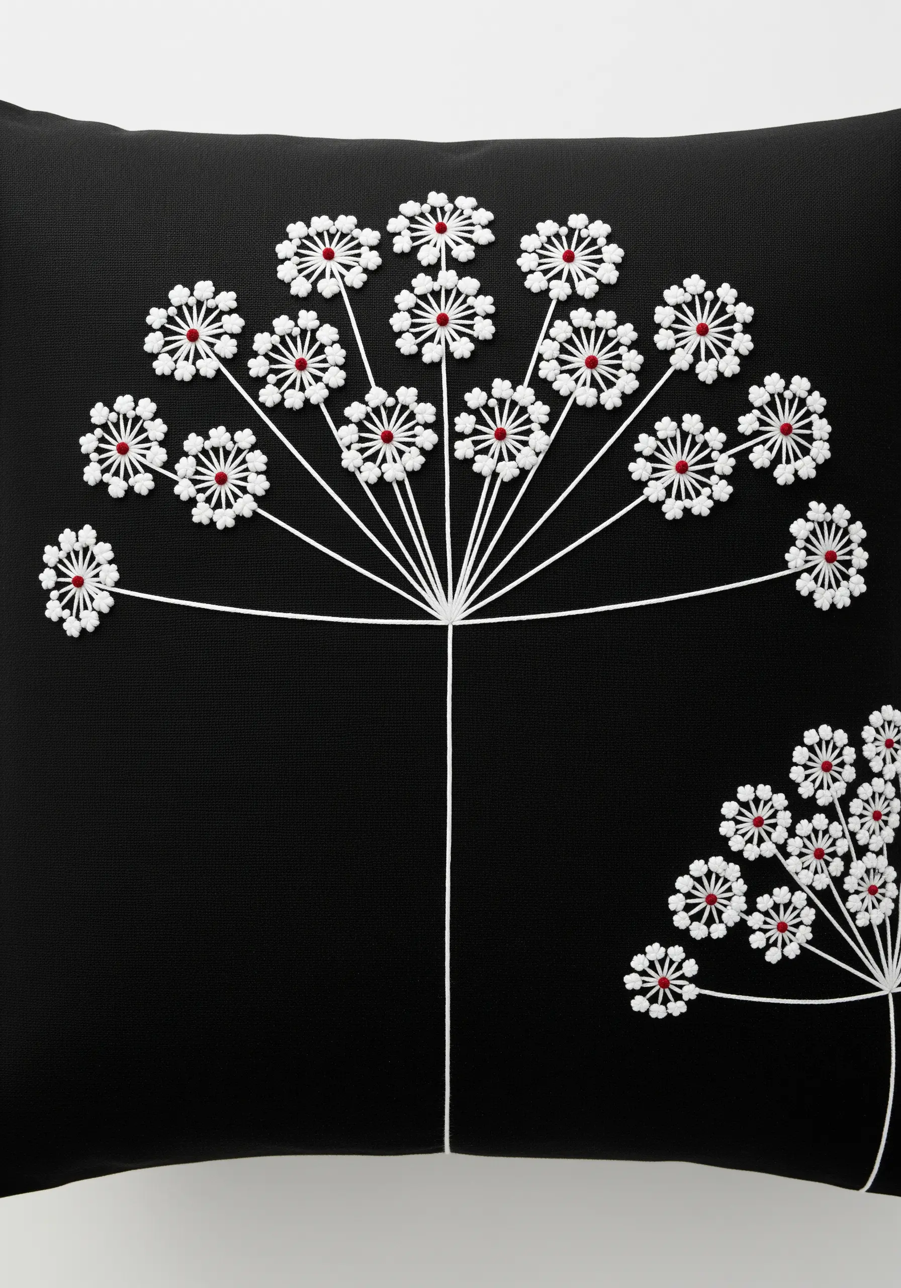 Graphic Queen Anne's Lace embroidered in white with red French knots on a black cushion.