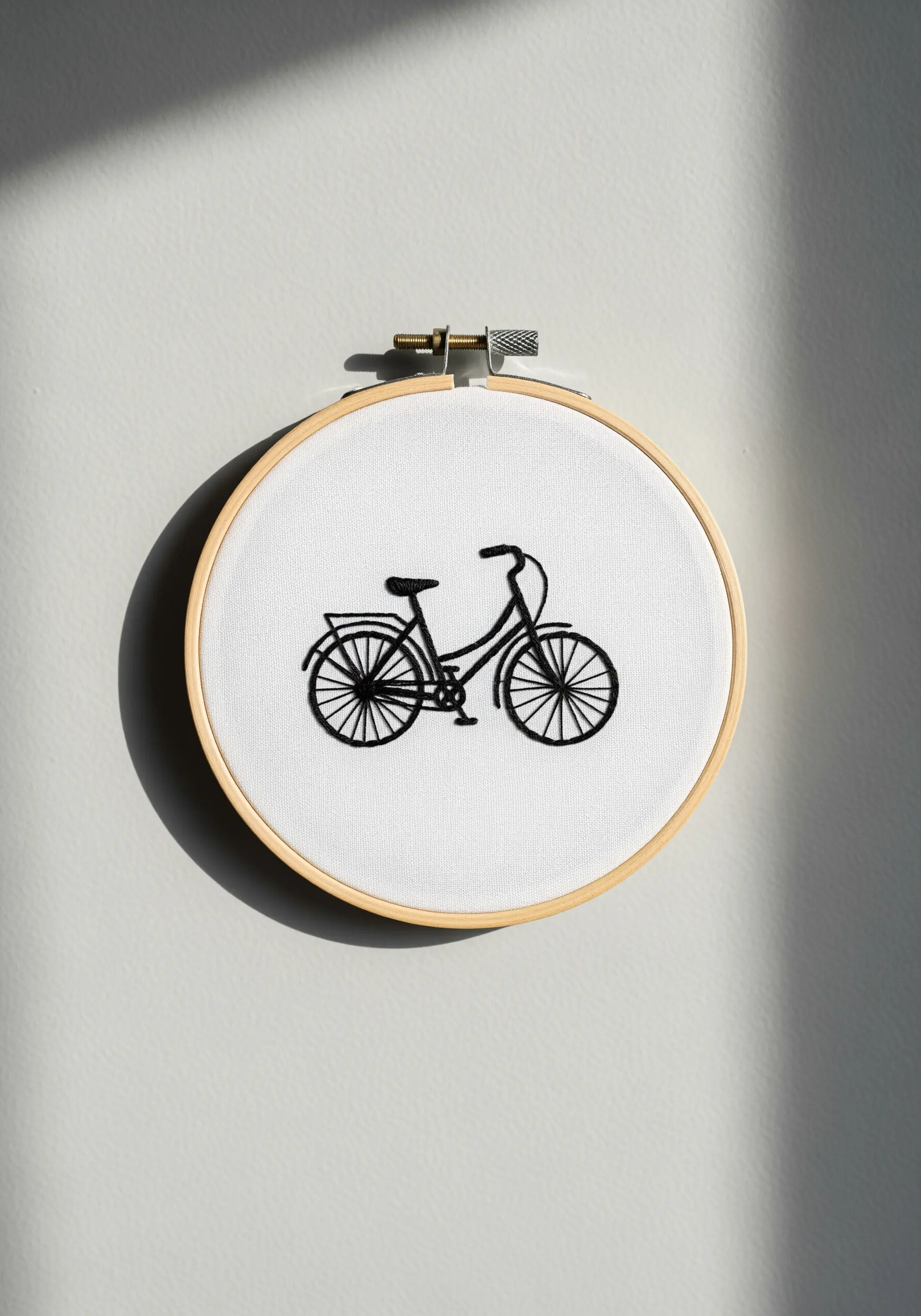A minimalist line art embroidery of a bicycle in black thread on a white background.