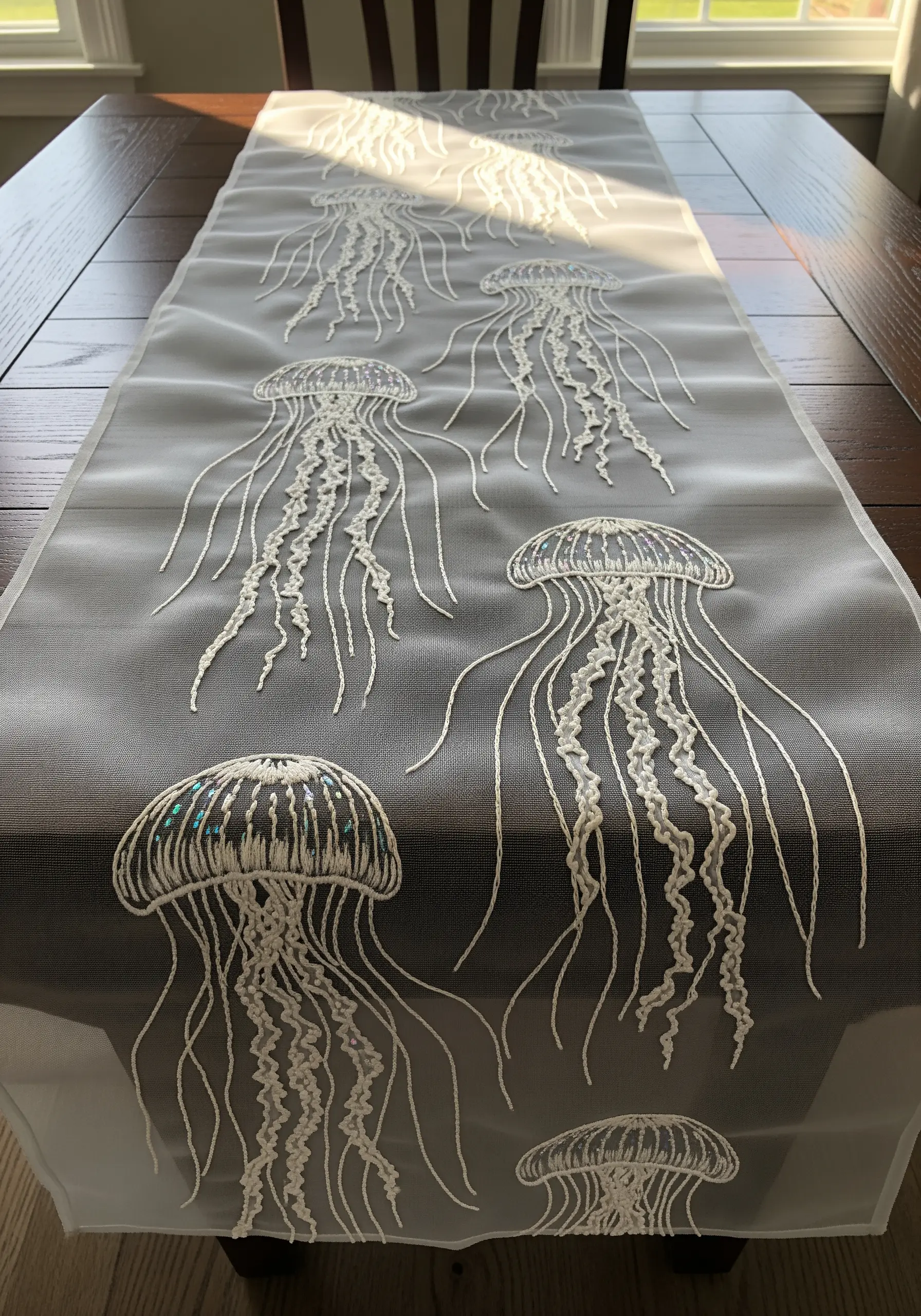 White jellyfish embroidered on a sheer table runner, creating a transparent effect.