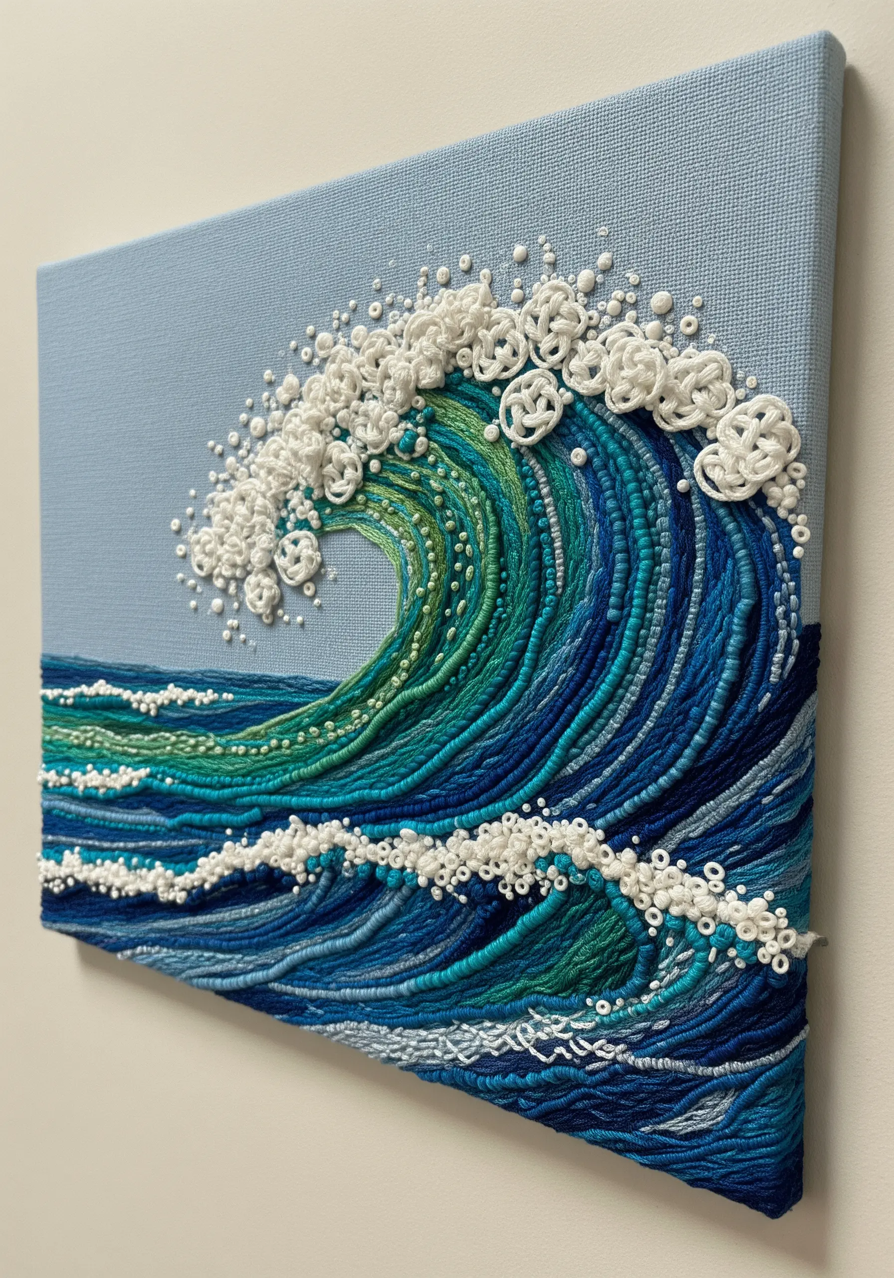 An embroidered ocean wave made with couched thread and dense white French knots for seafoam.