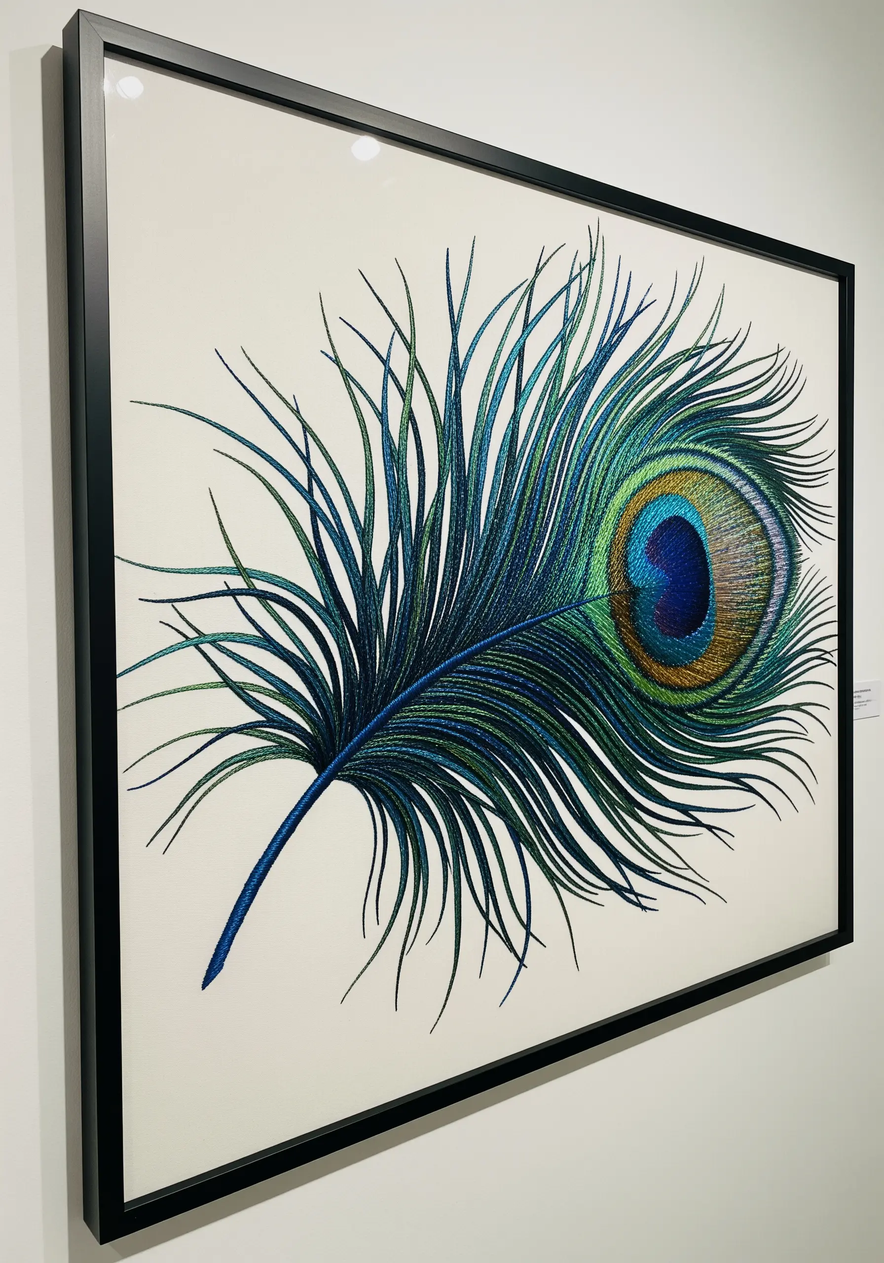 A highly detailed, framed embroidery of a peacock feather with shimmering, iridescent threads.