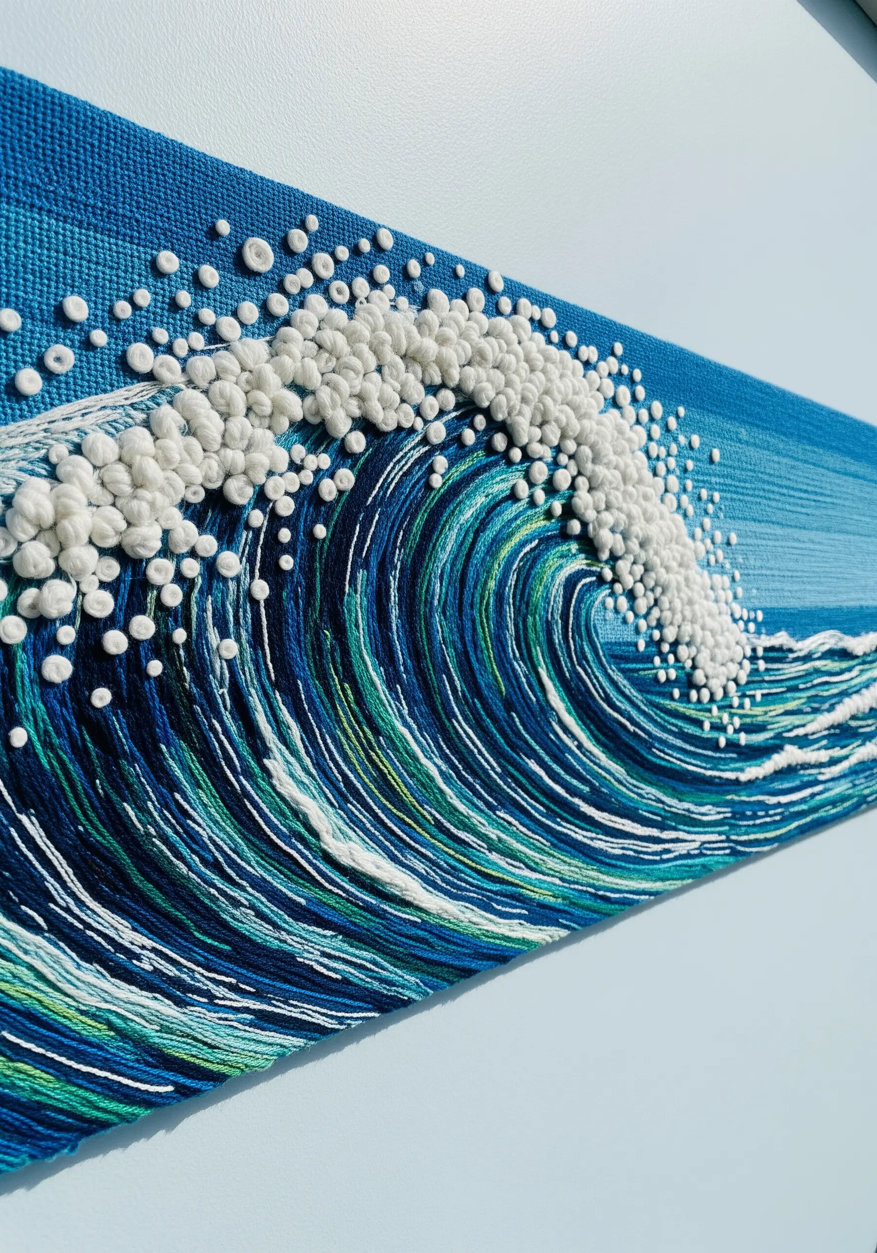 A dimensional embroidery of an ocean wave, with French knots for sea foam and long stitches for water.