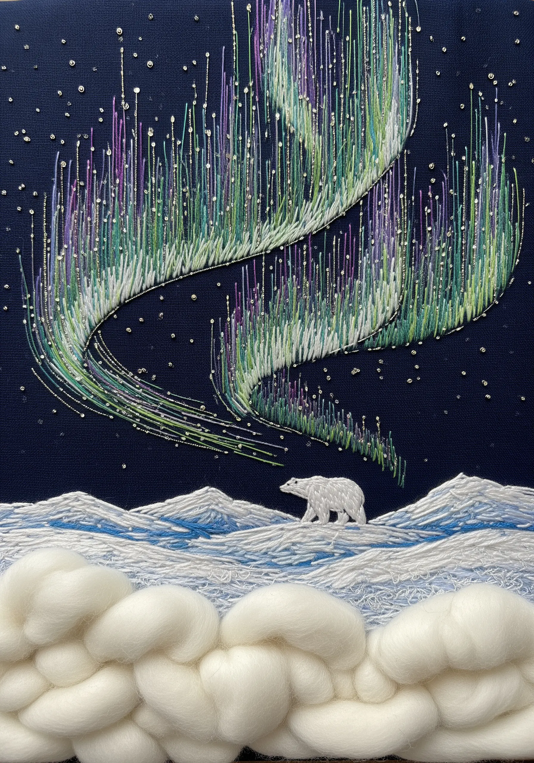 Embroidery of the northern lights with a polar bear and wool roving snow.