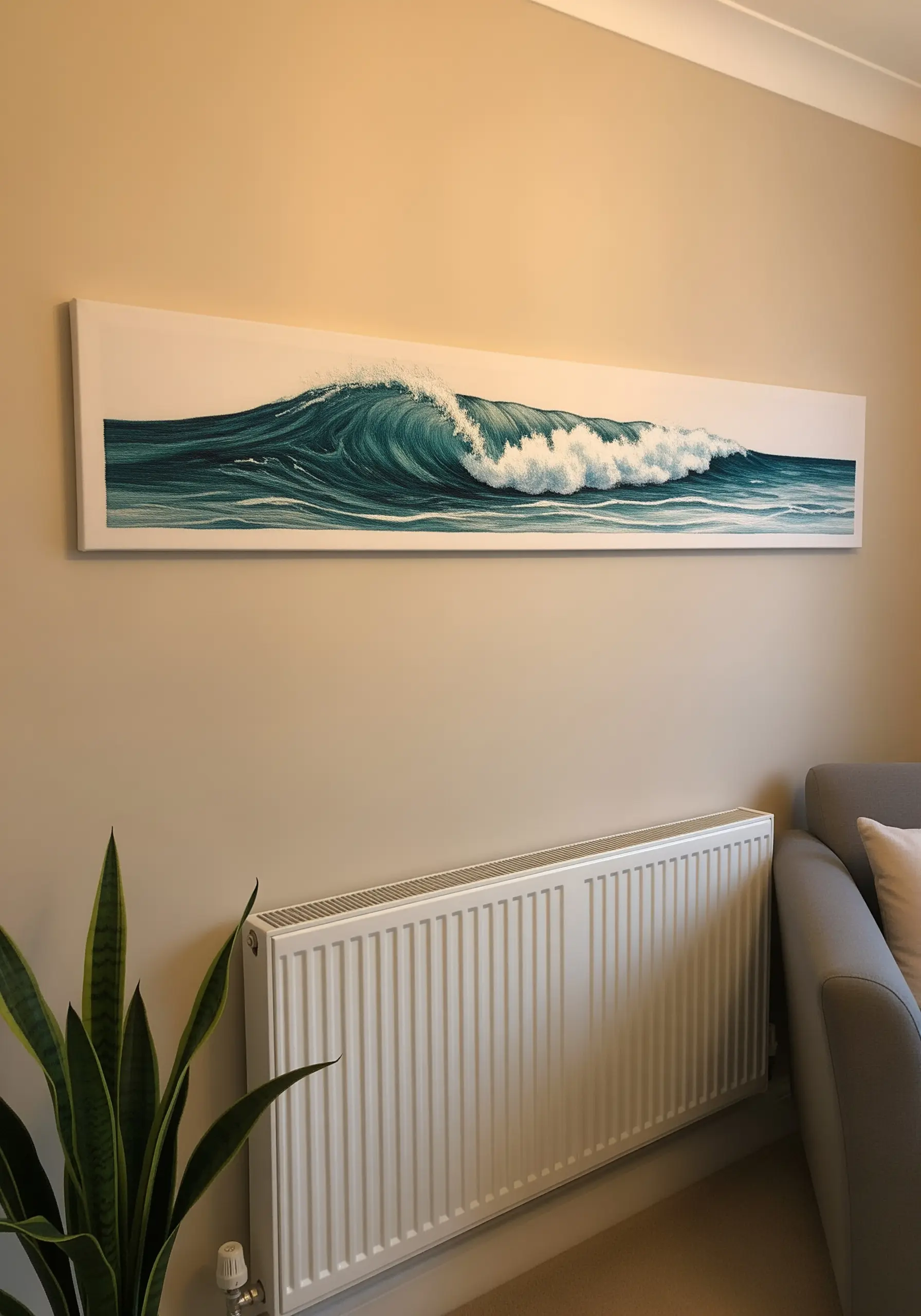 A long, panoramic framed embroidery of a cresting ocean wave hanging on a beige wall.
