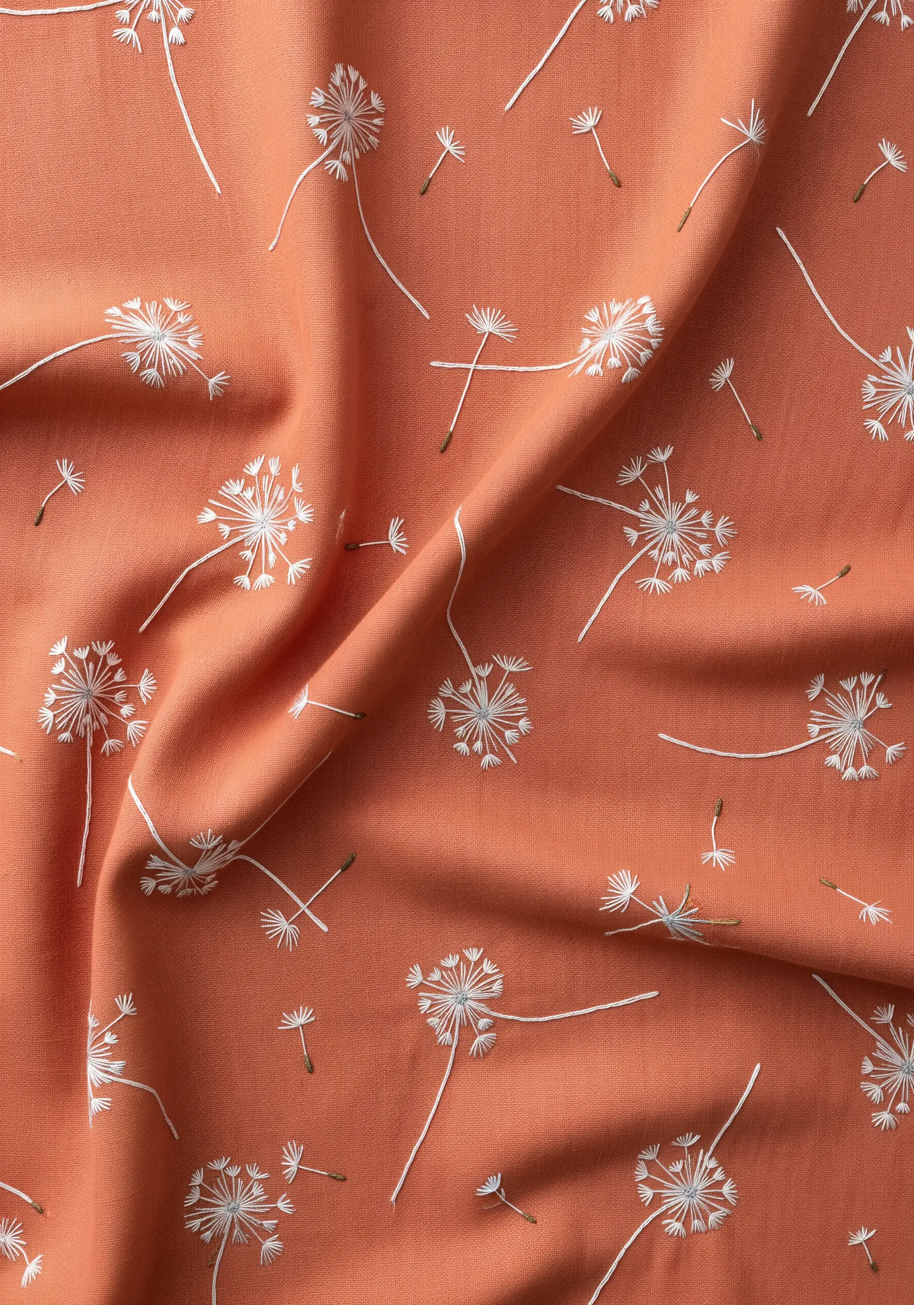 An all-over pattern of white embroidered dandelion clocks on a terracotta-colored fabric.