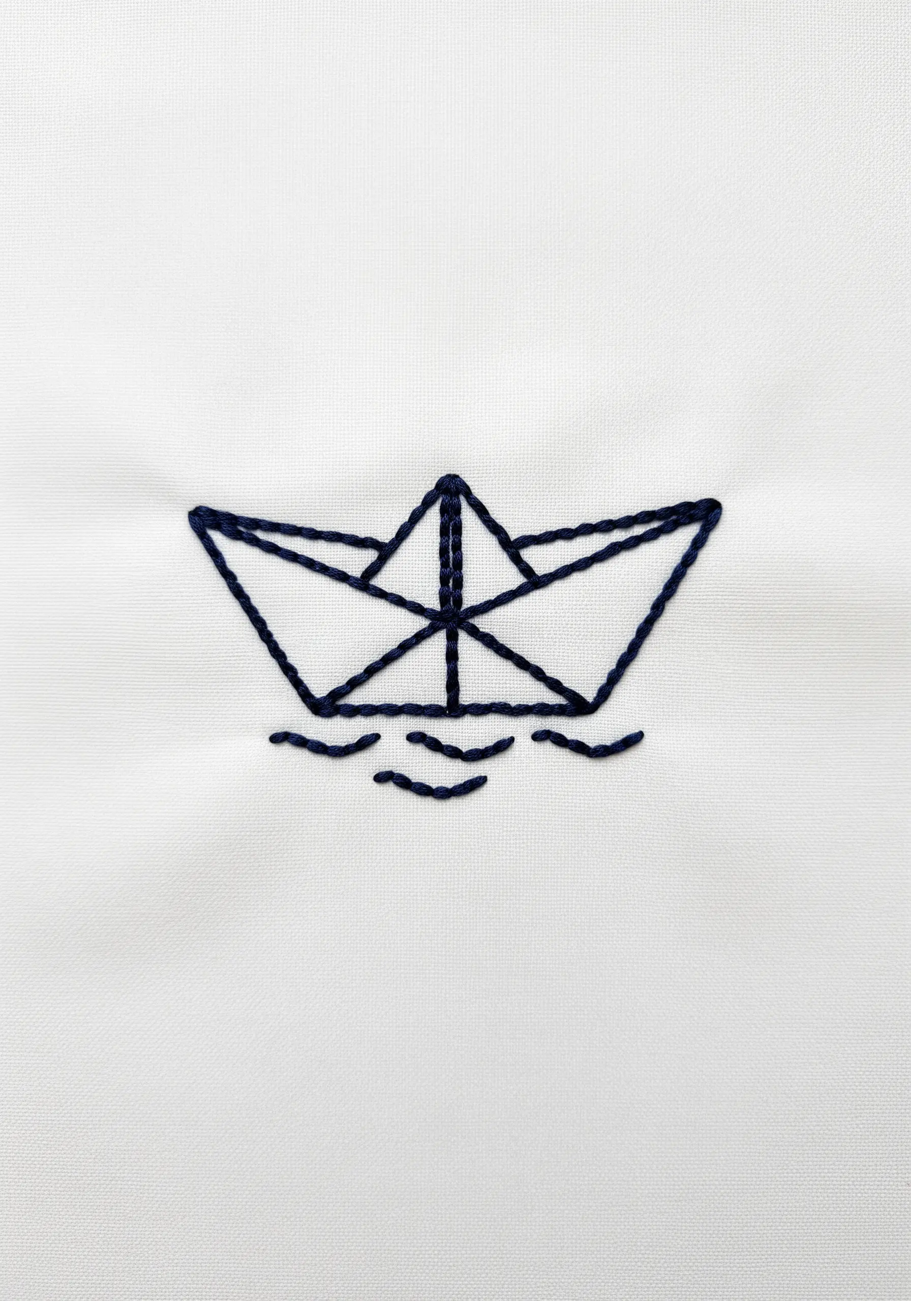 Minimalist line art of a paper boat and small waves in dark thread.