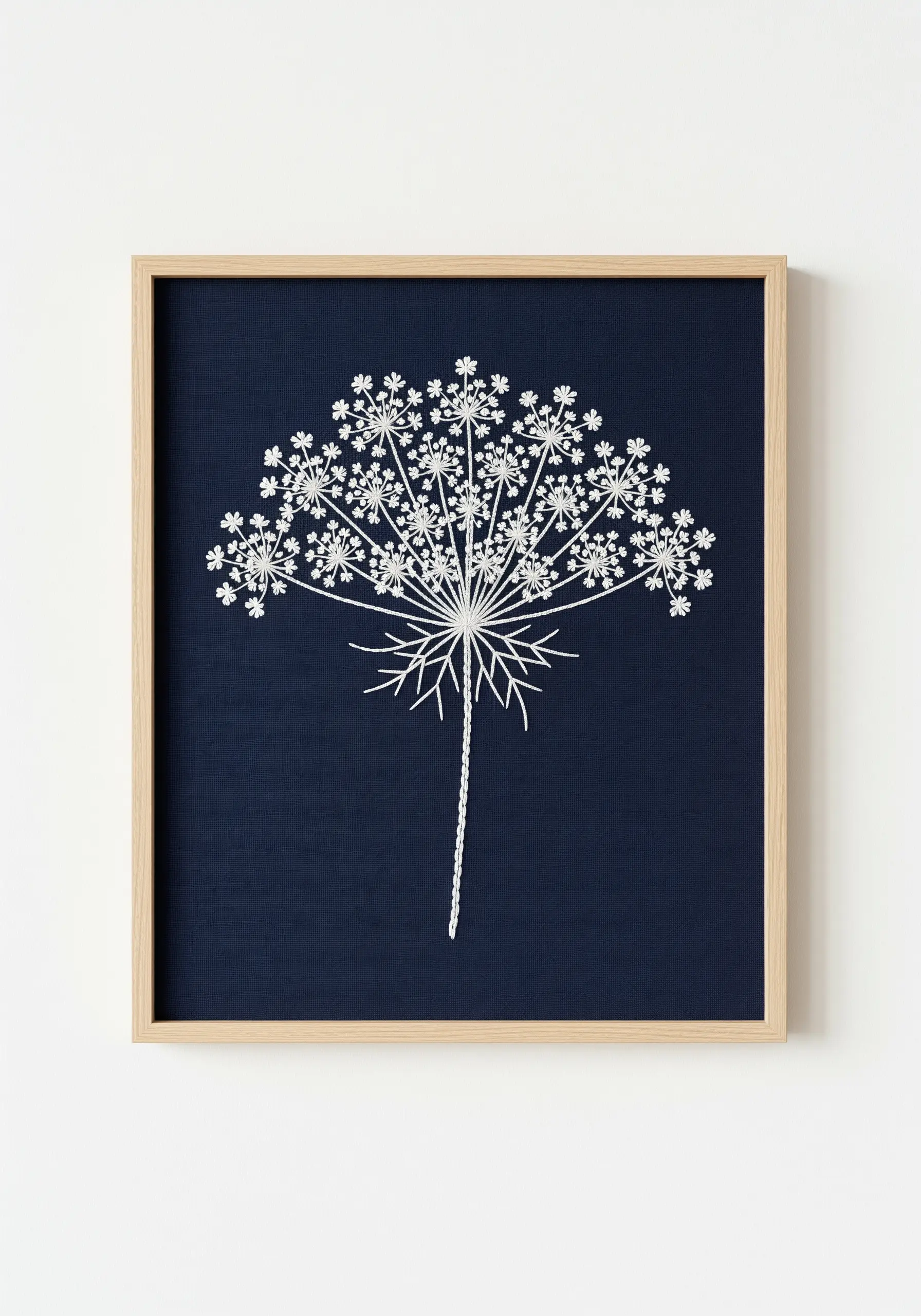 White thread embroidery of a Queen Anne's lace silhouette on dark navy fabric.