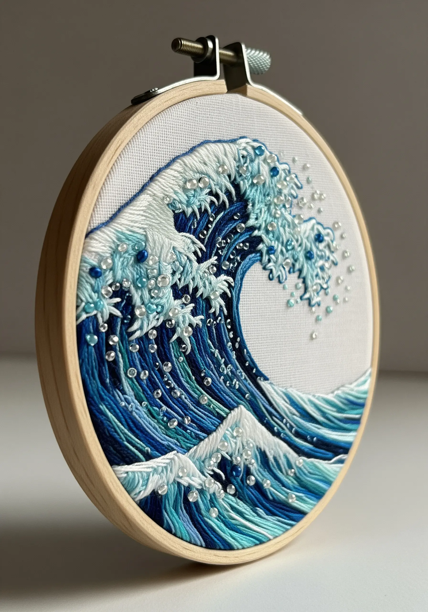 Embroidered ocean wave in a hoop with clear beads representing sea spray.