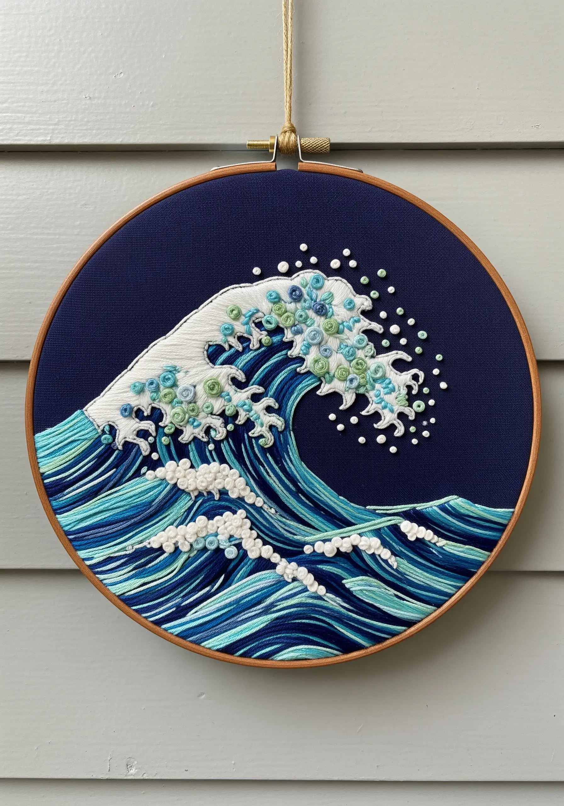 Embroidered wave with French knots and directional satin stitch on dark blue fabric.