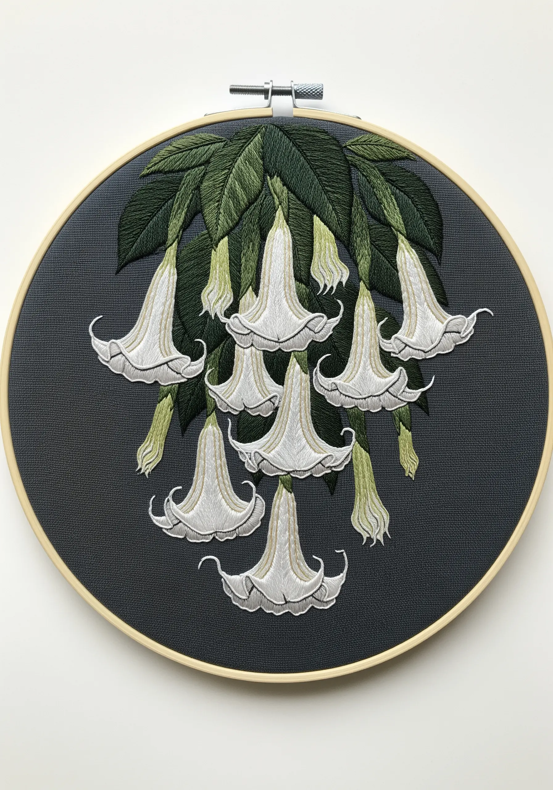 Embroidery of white, bell-shaped Angel's Trumpet flowers hanging from a branch on grey fabric.