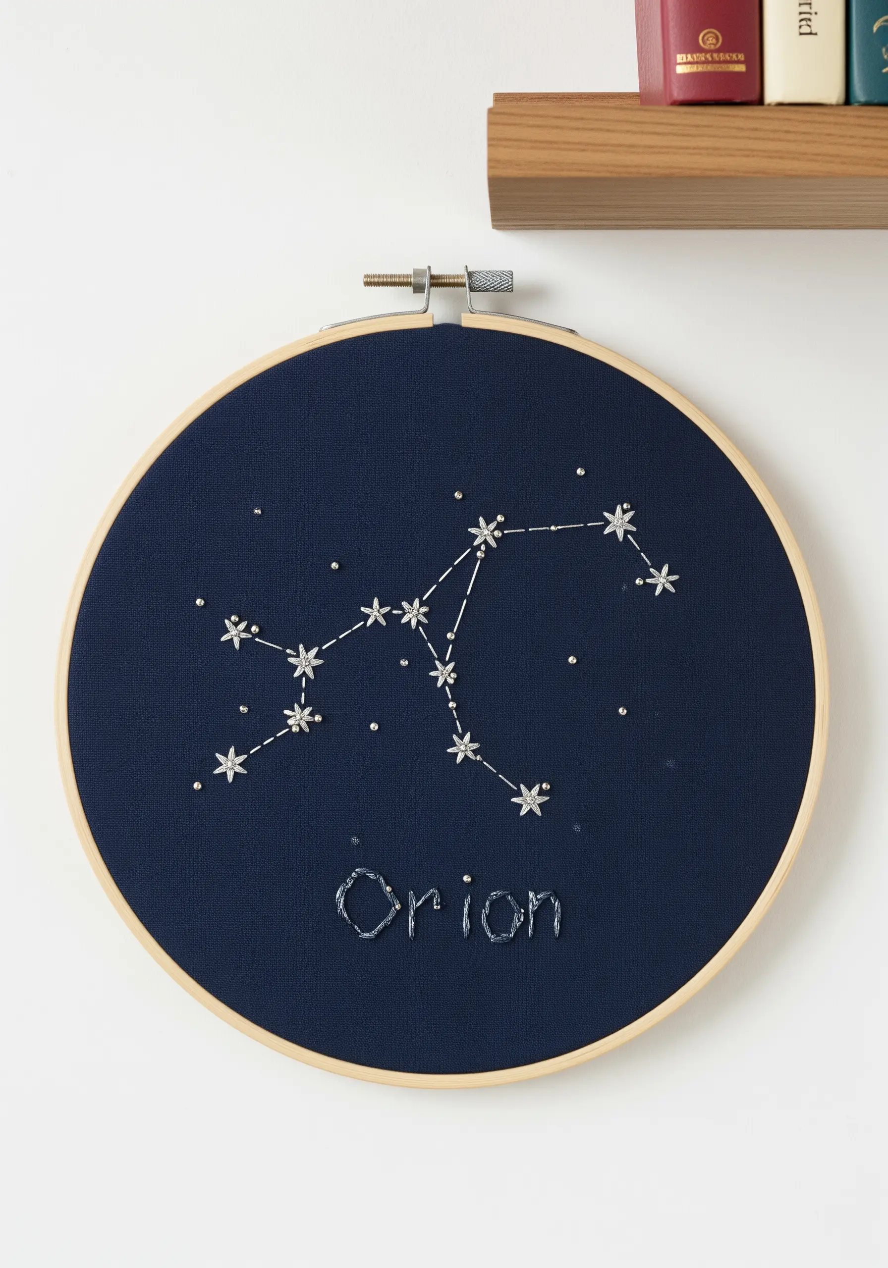 Orion constellation embroidered with white thread and silver beads on dark navy fabric.