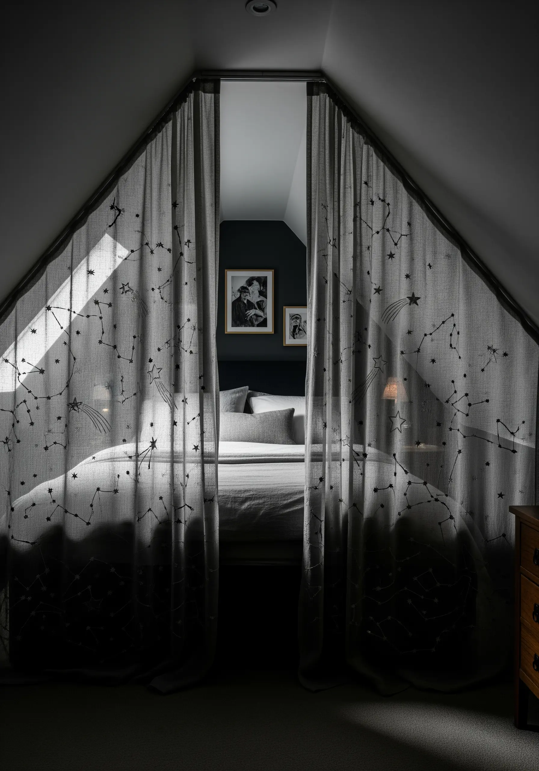 Delicate constellation and star patterns embroidered on sheer, dark gray bedroom curtains.
