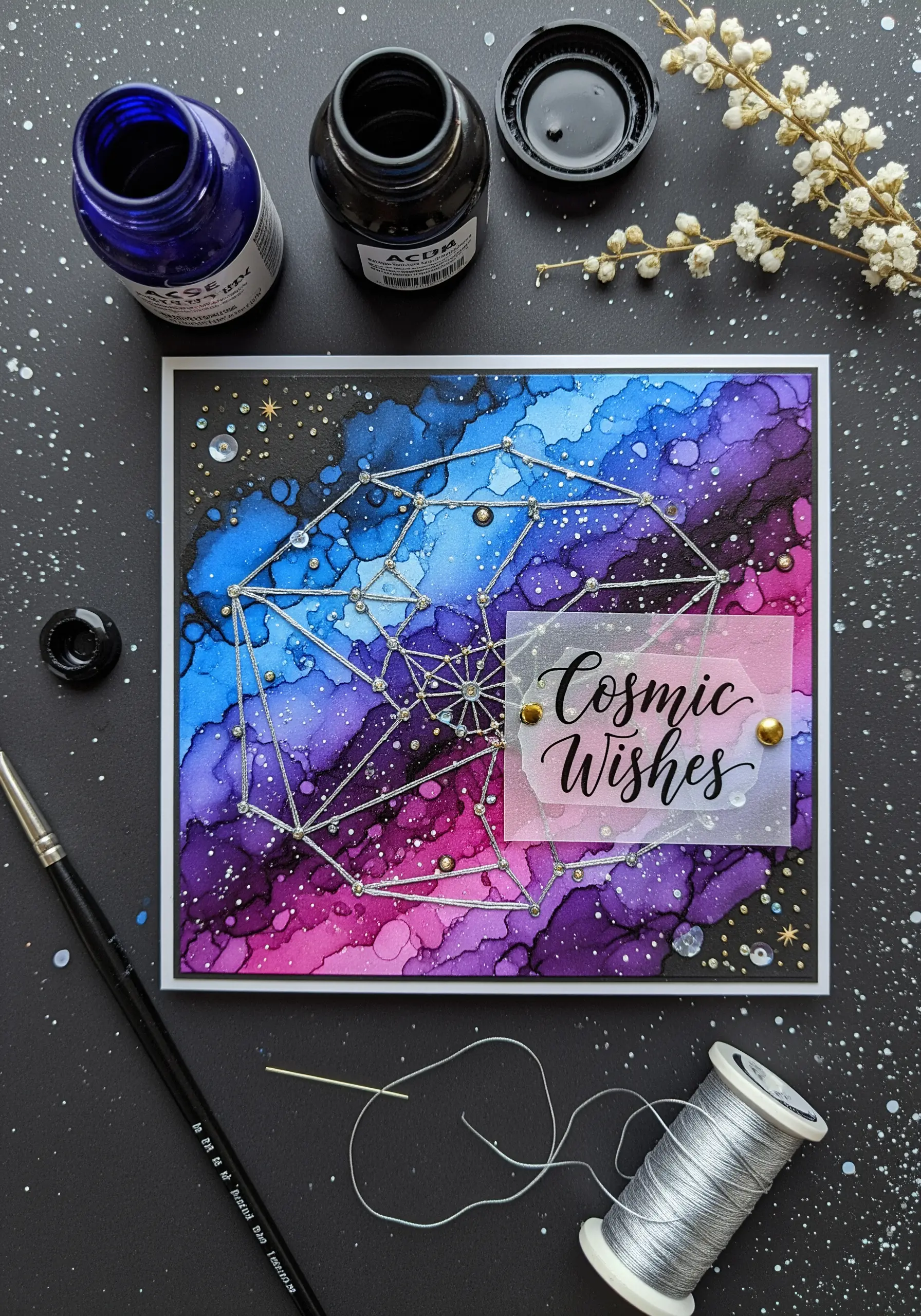 Geometric constellation stitched with silver thread over a galaxy alcohol ink background.