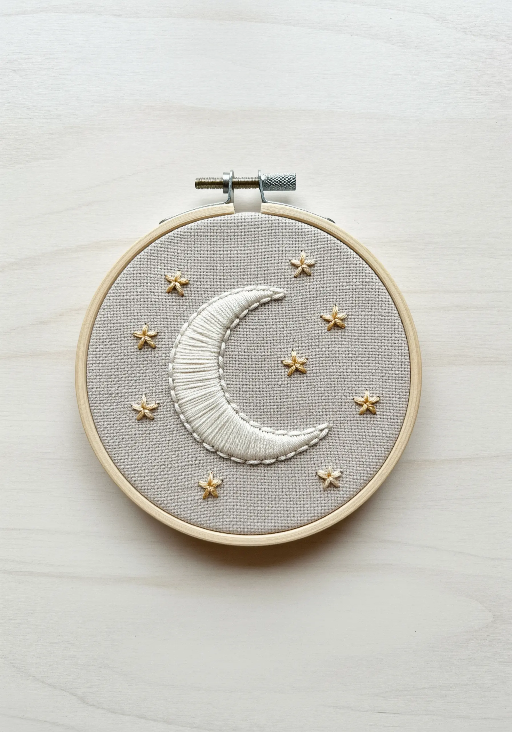 Padded satin stitch moon with metallic thread stars on gray evenweave fabric.