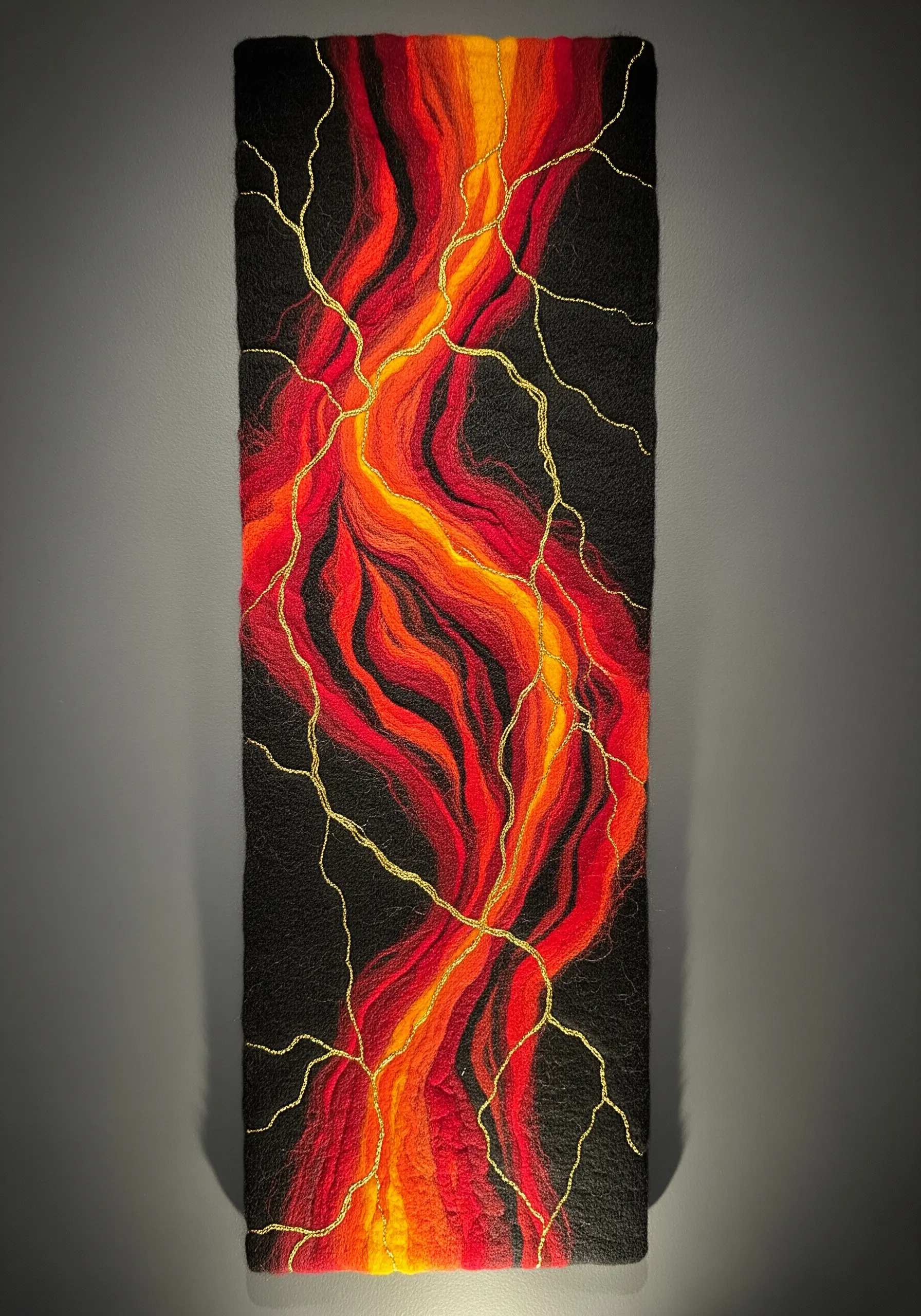 A felted wall hanging with red and orange fibers, stitched with gold thread in a kintsugi-like pattern.