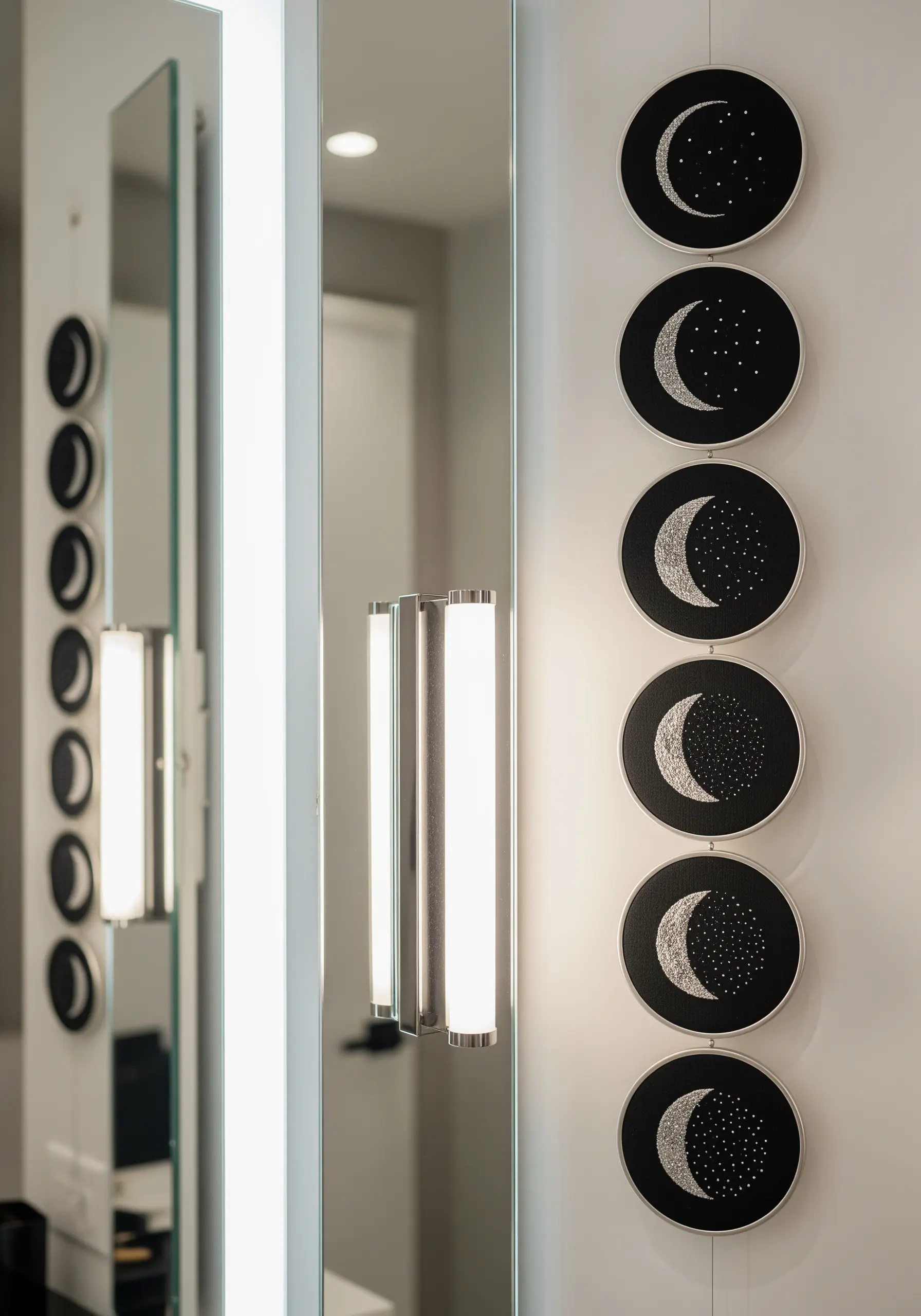 A vertical series of small embroidery hoops depicting the phases of the moon in silver thread