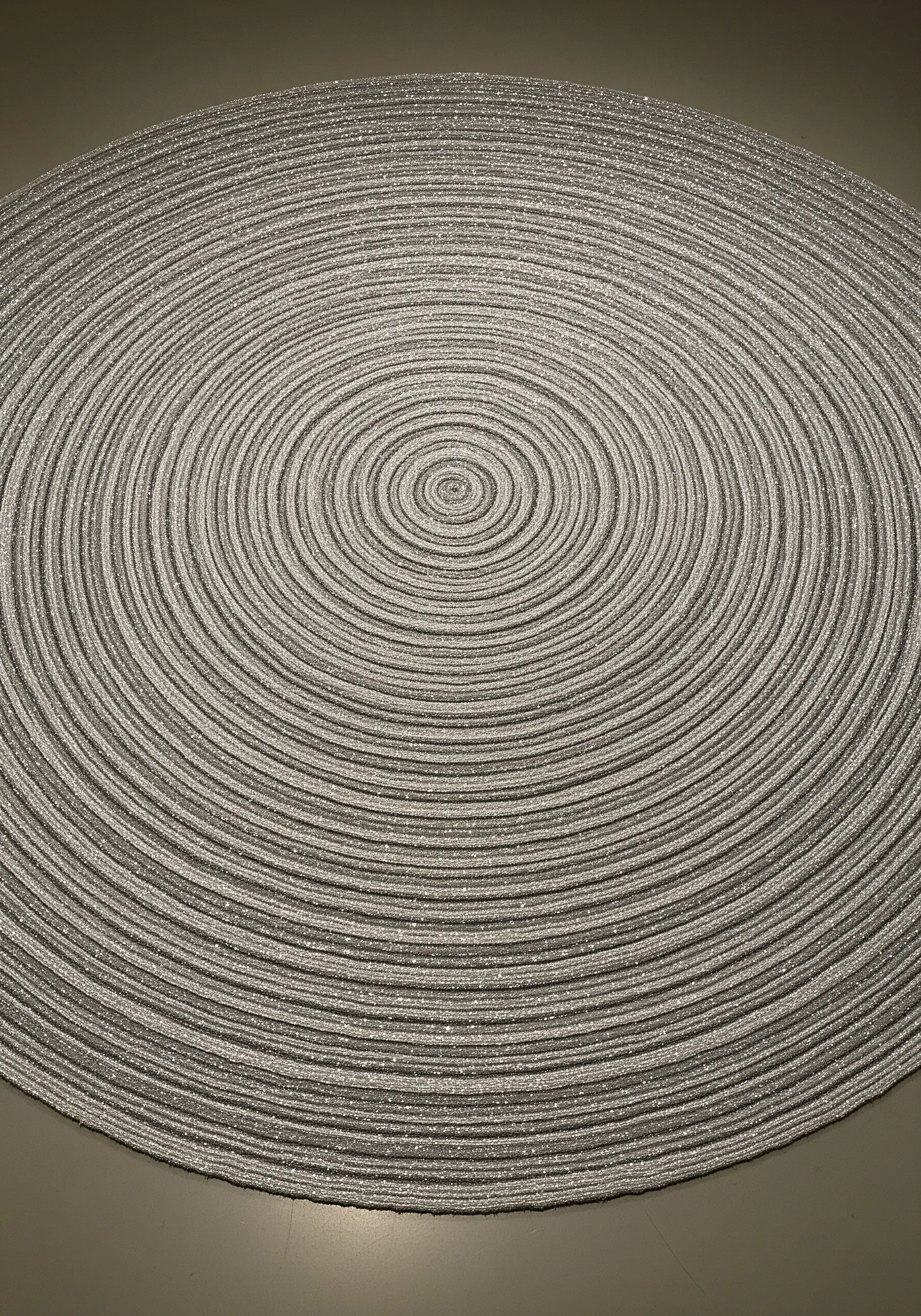 A large, flat spiral made of coiled silver cord creates a hypnotic optical illusion on the floor.