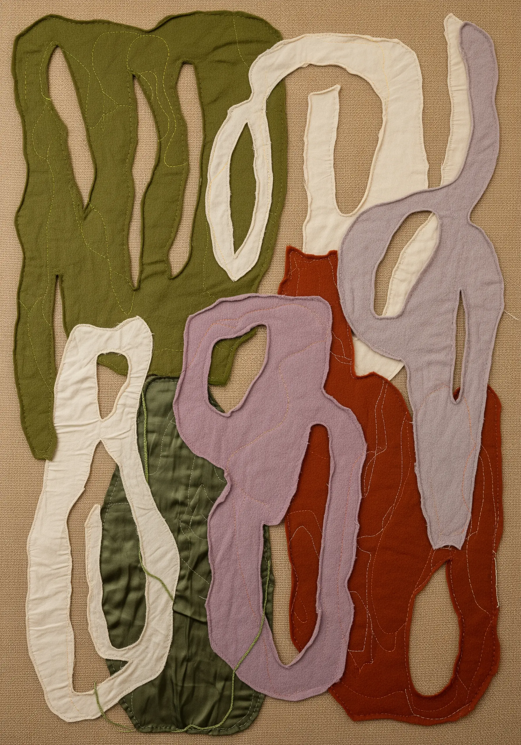 Abstract fabric collage with organic shapes in earthy tones, outlined with machine stitching.