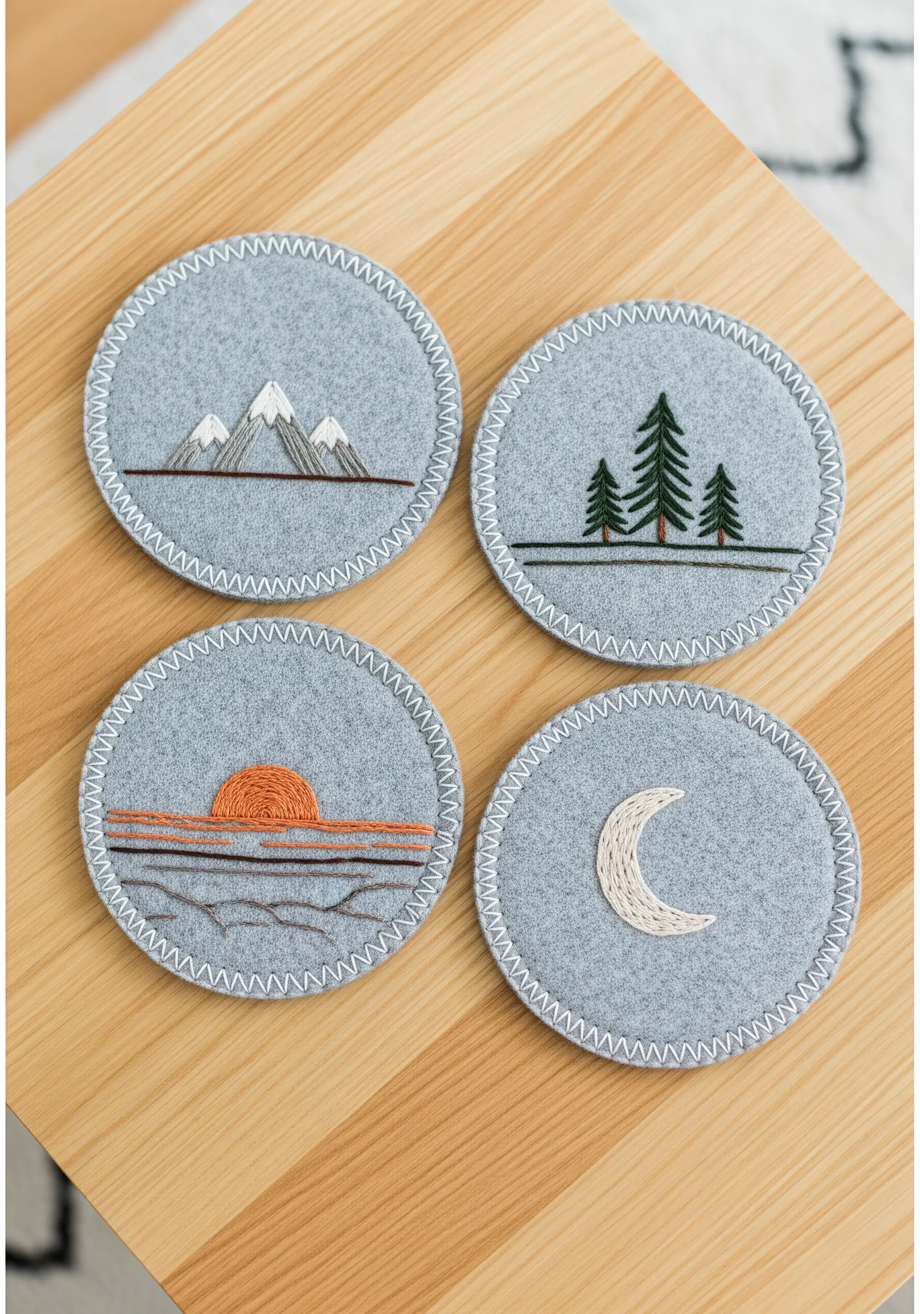 A set of four round felt coasters, each with a simple embroidered nature scene.